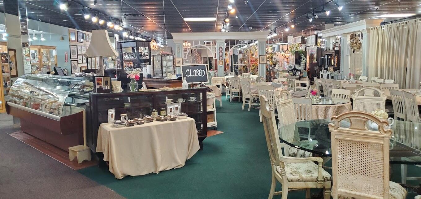 A cafe with vintage white chairs, glass tables, and display cabinets at Chocolate Angel Cafe & Tea Room - High Street.