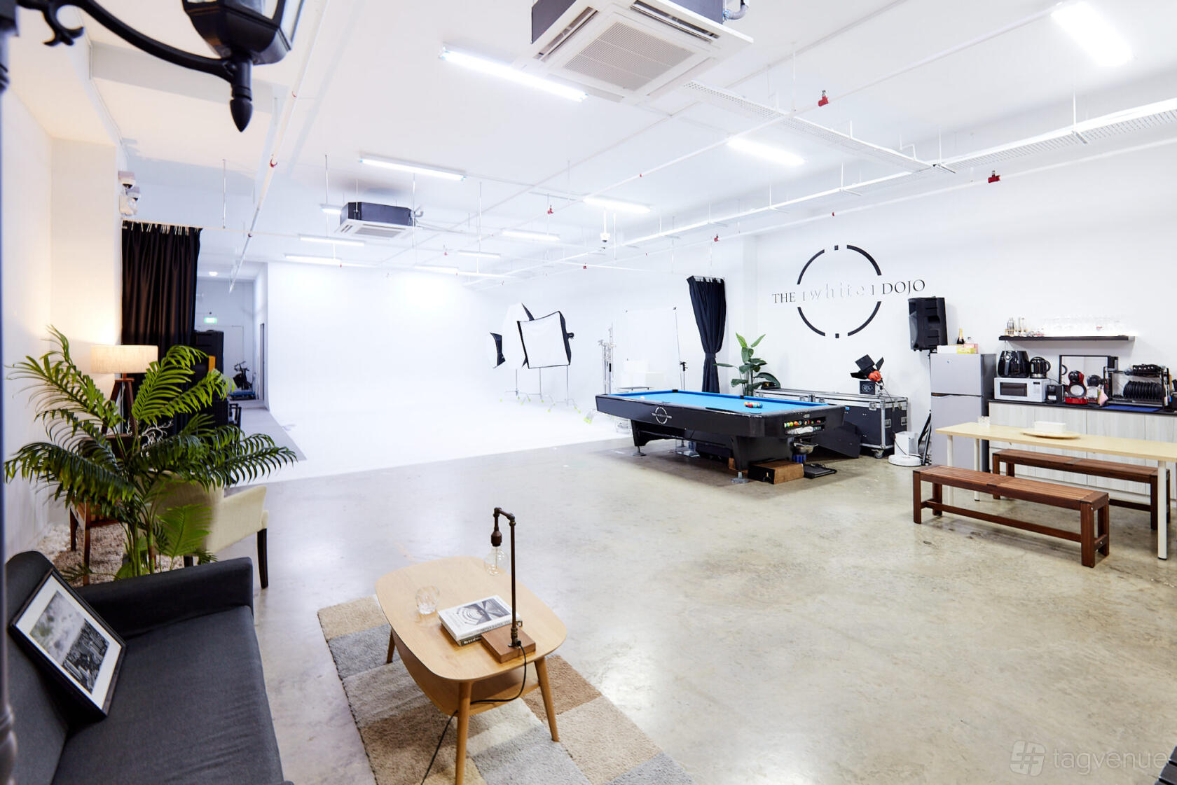 A photo studio with a cyclorama wall, pool table, lounge seating, and coffee station at The White Dojo.