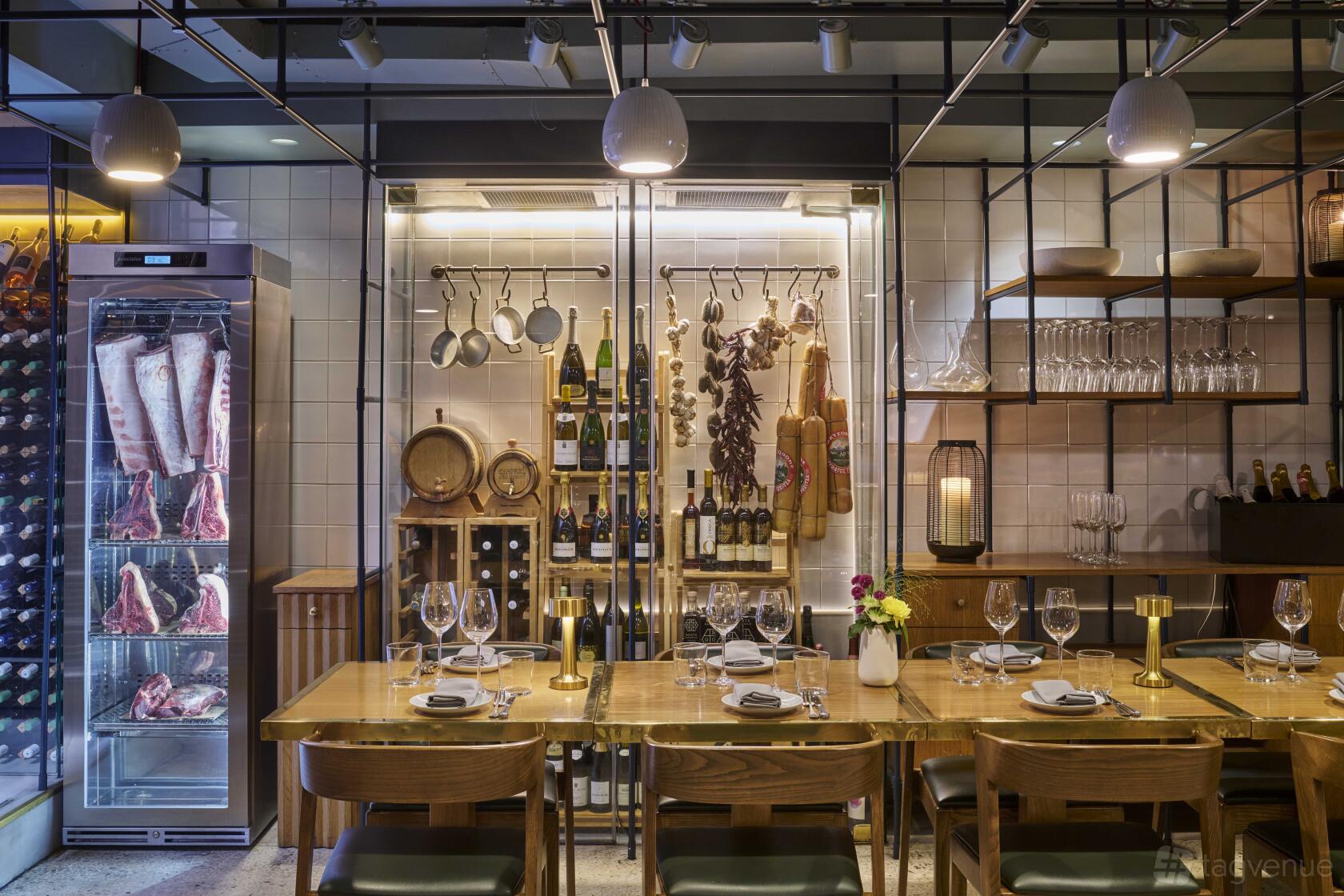 A restaurant with a wooden dining table set for six, open shelving, and a display of hanging pots and wine at OPSO.