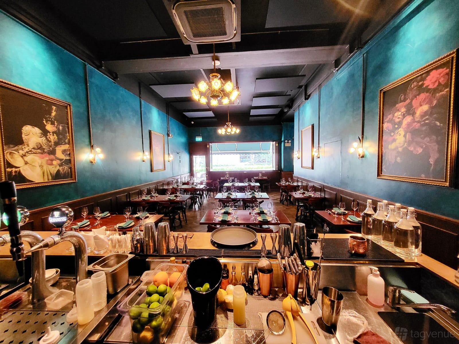 A restaurant with teal walls, chandeliers, framed artwork, and set dining tables at Quay House.
