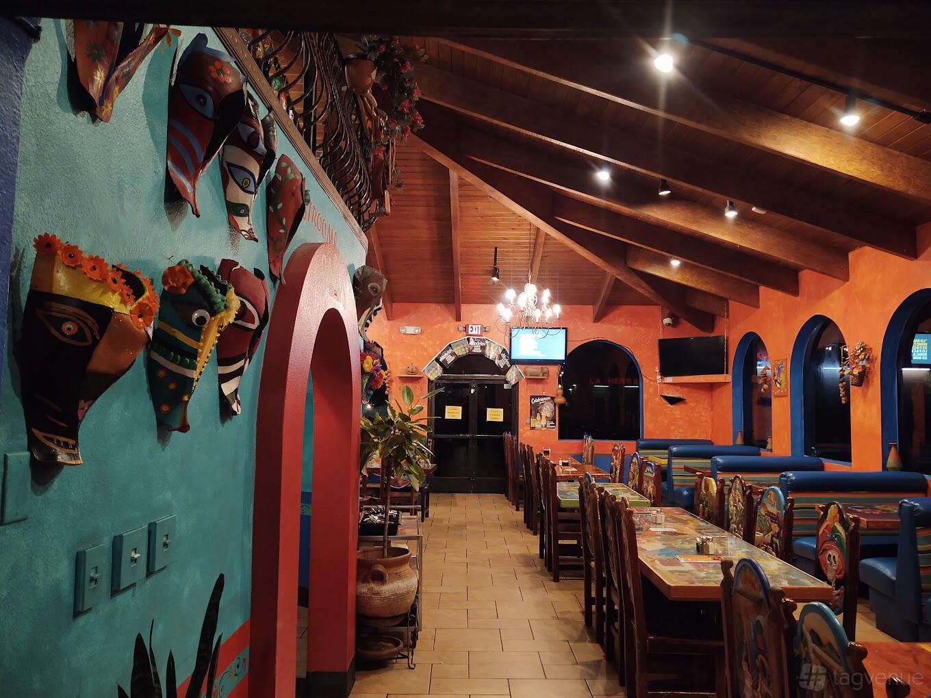 A restaurant with colorful walls, decorative masks, wooden ceiling beams, and long tables at Bonito Michoacan Mexican Restaurant.