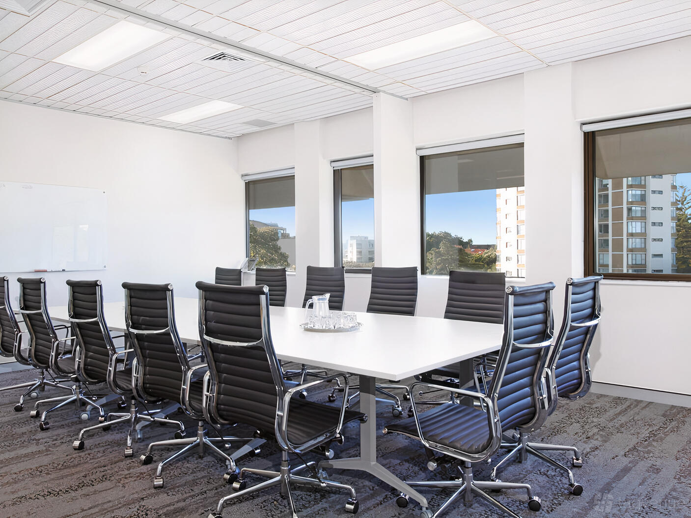 An event space with a long white conference table, black leather chairs, large windows, and a whiteboard at Workspace365 Edgecliff Sydney.