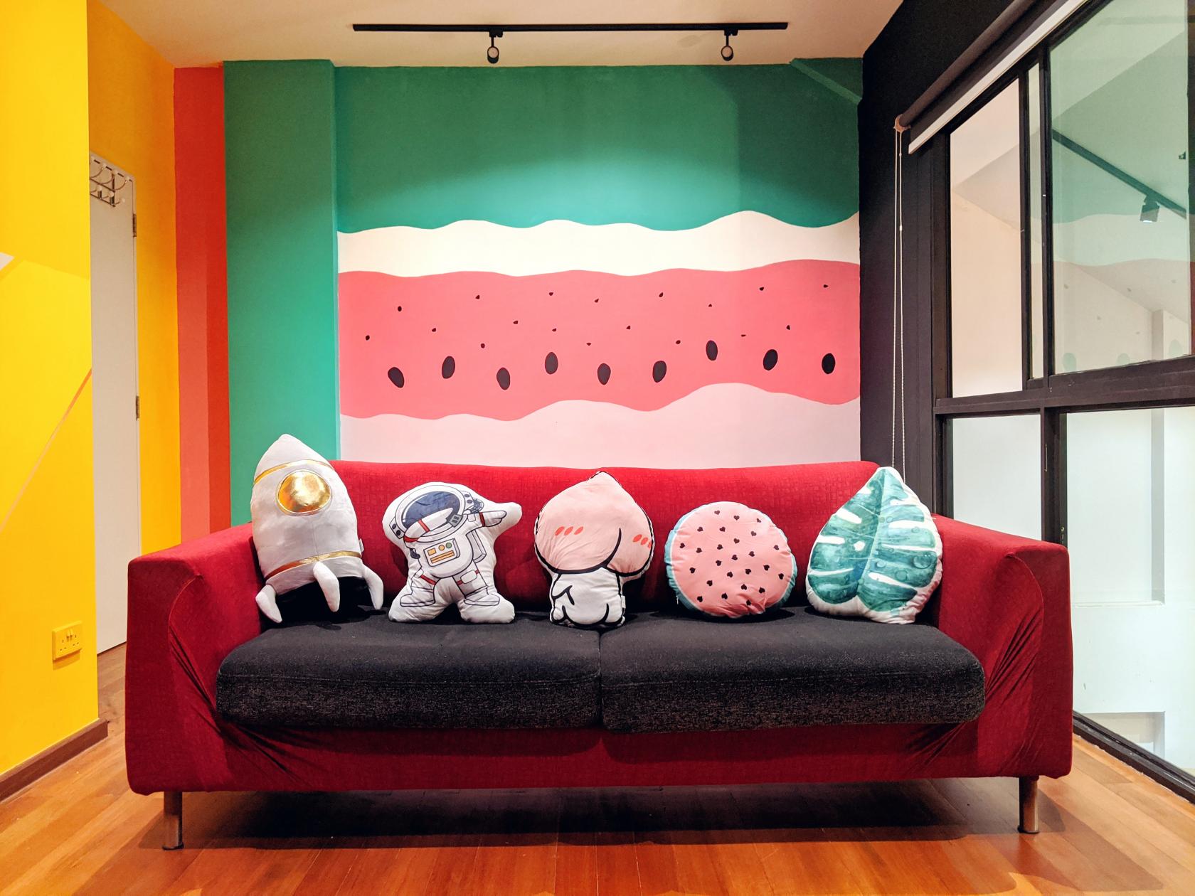 A therapy room with playful wall art and a red sofa decorated with themed pillows at The Common Good (TCG)