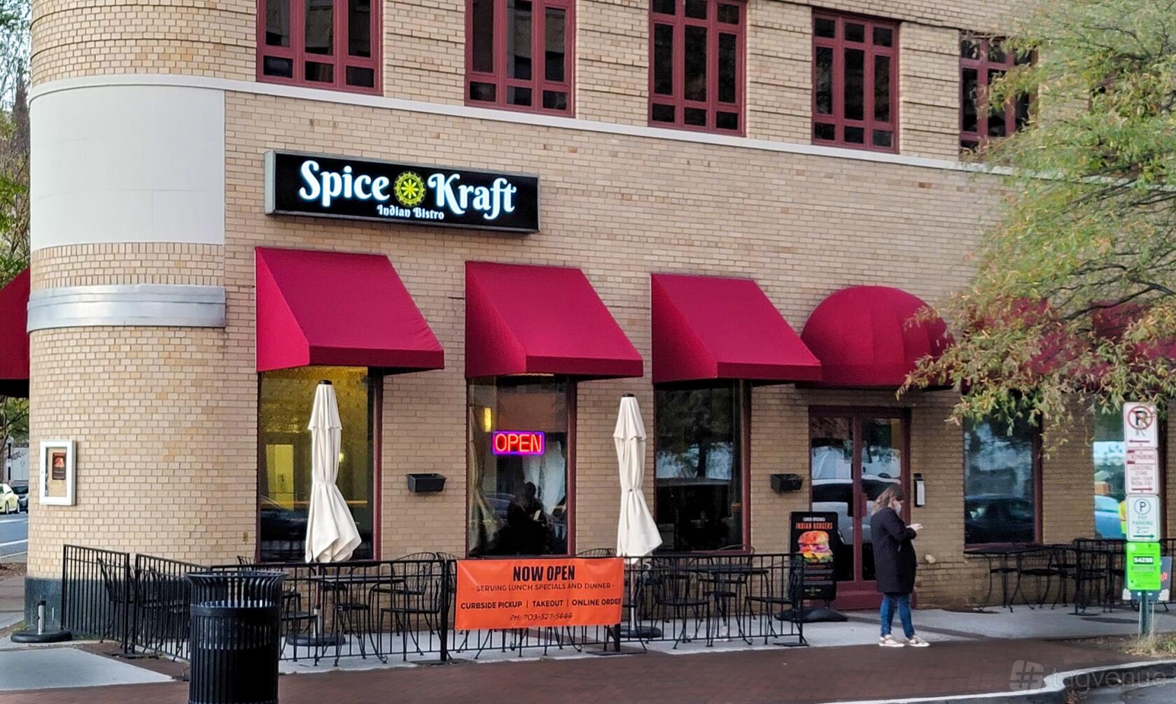 A restaurant with red awnings, outdoor seating, and large windows at Spice Kraft Indian Bistro Arlington.