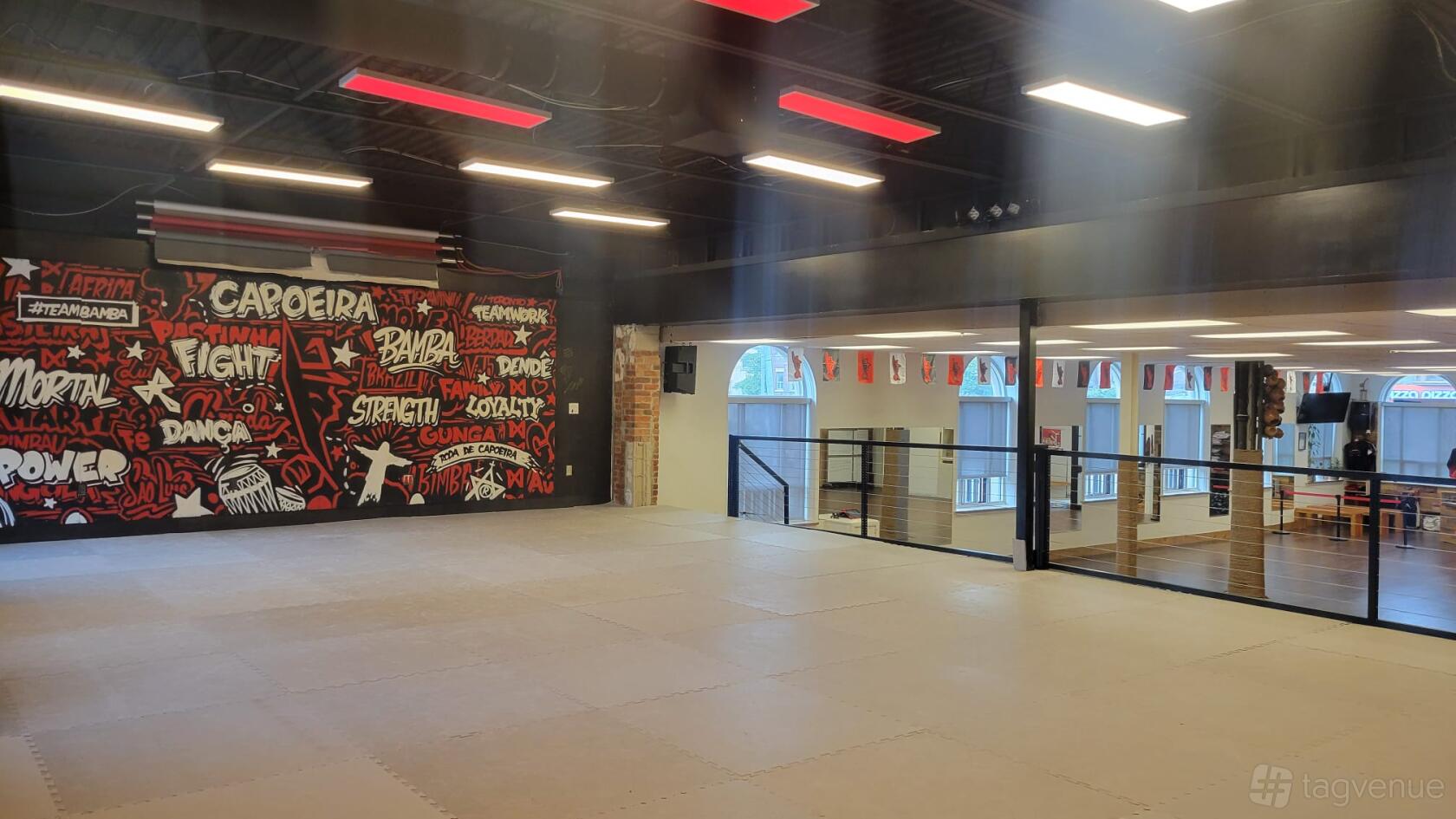 A yoga and pilates studio with padded flooring, graffiti mural wall, and floor-to-ceiling windows at Casa de Bamba.