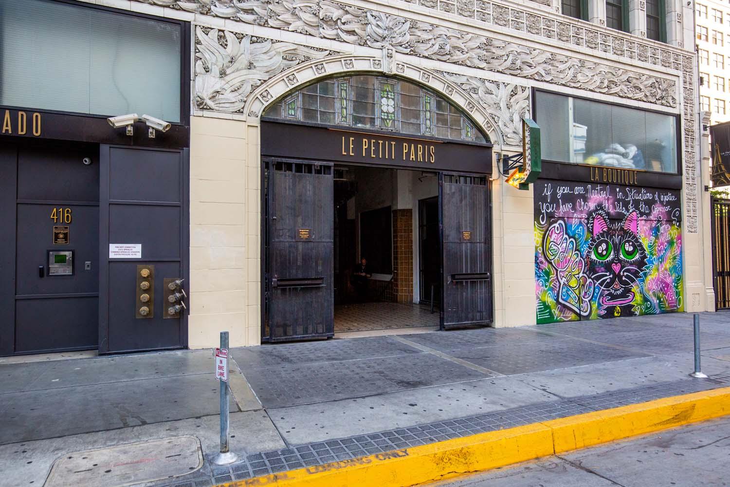 A pub entrance with ornate architectural details and colorful street art mural at The Stowaway DTLA