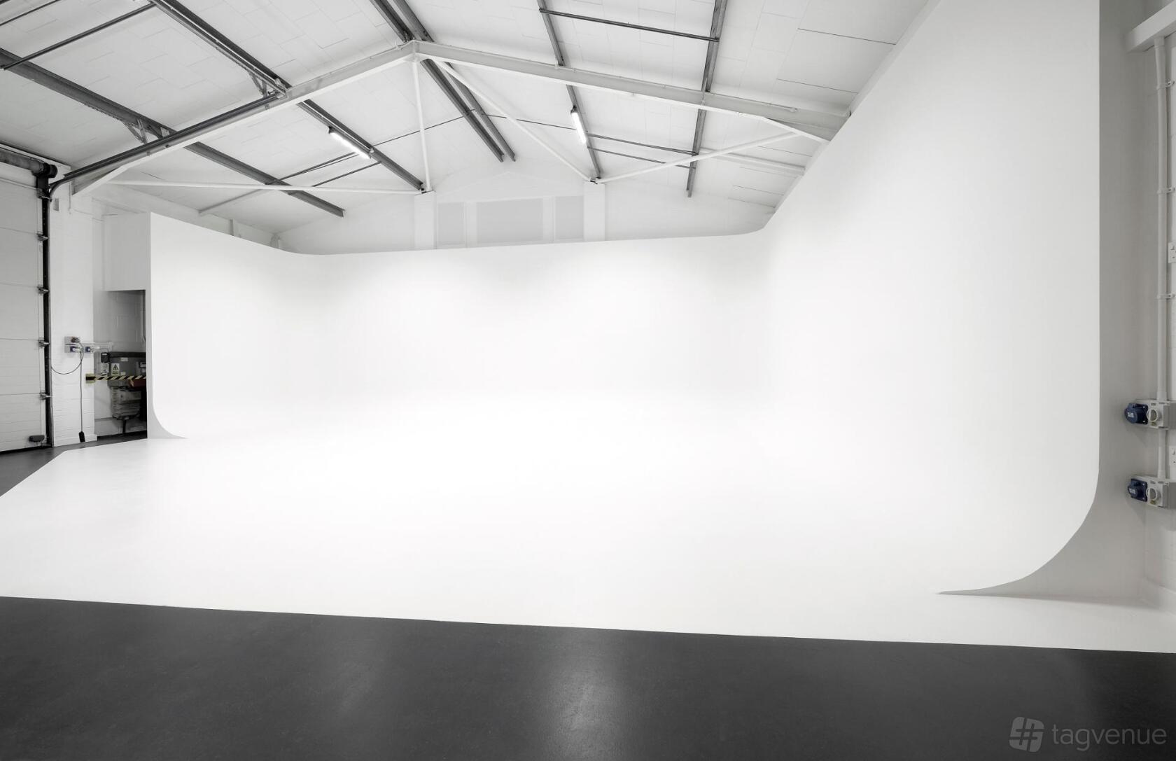 A photo studio with a large white cyclorama wall and high ceilings at Creative Klousions.