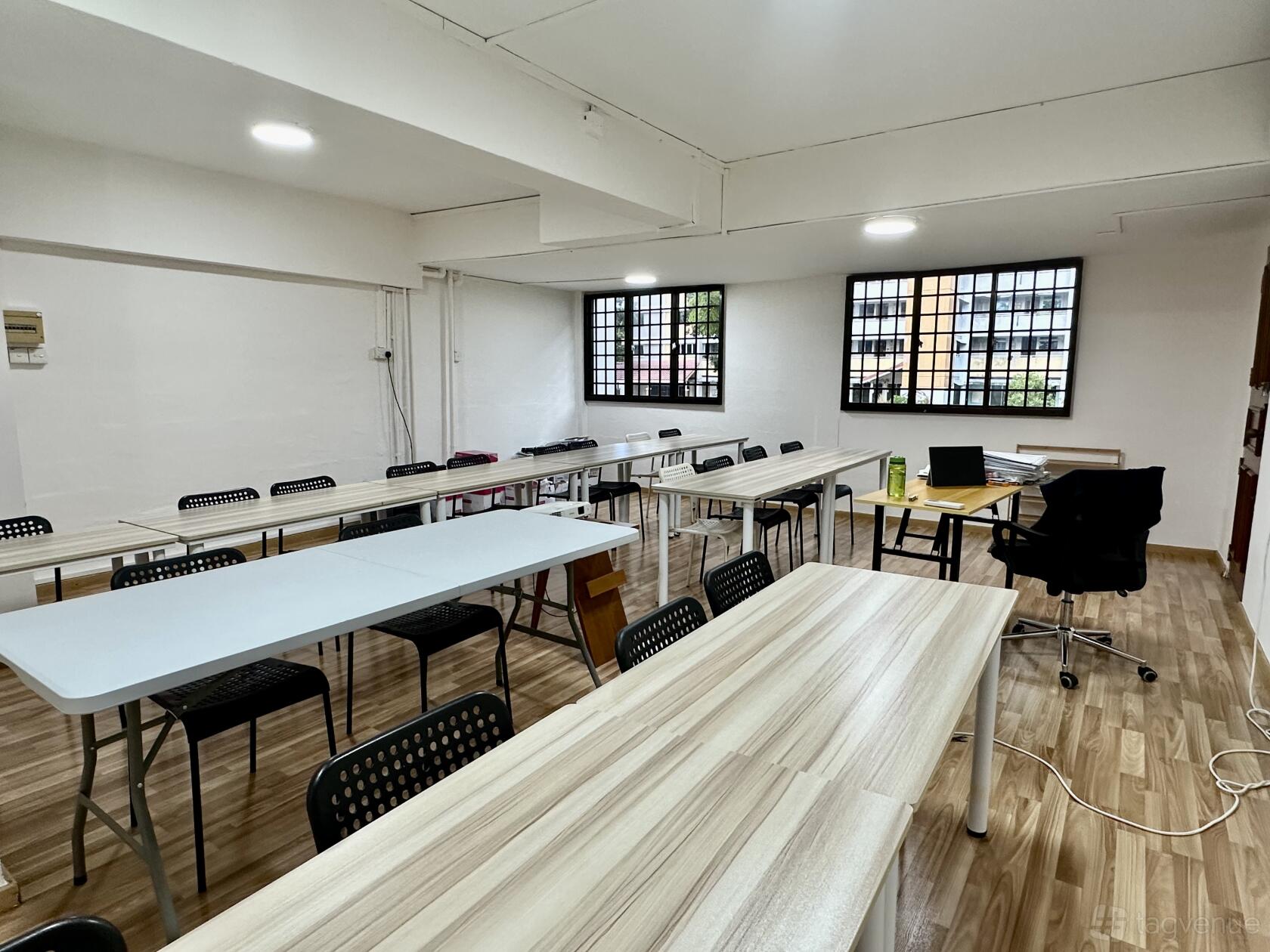 A meeting room with long wooden tables, black chairs, large windows, and wood-look flooring at The Winning Studio.