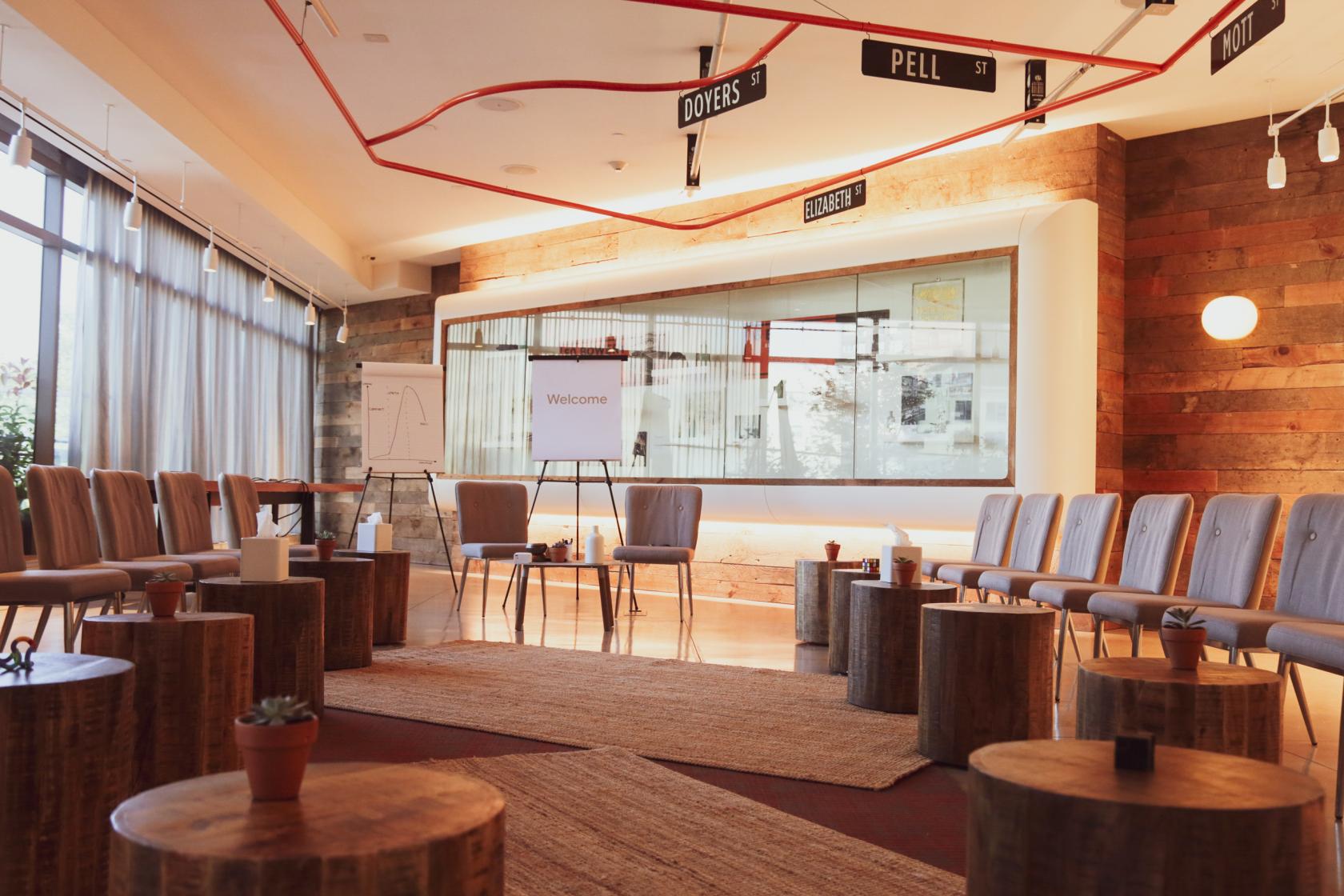 A hotel event space with wood panel walls, natural light, and rows of chairs arranged in a circle at Hotel 50 Bowery.