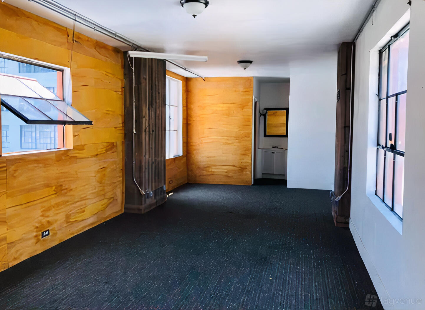 A penthouse with large windows, yellow textured walls, and dark carpeting at 824 Building.