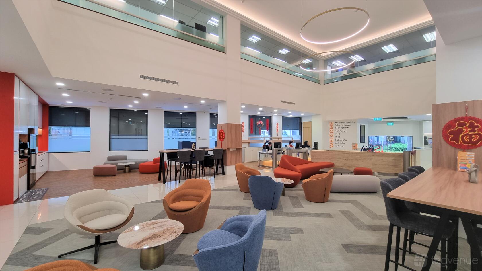 A modern lounge with colorful armchairs, round tables, and floor-to-ceiling windows at ISCA House.