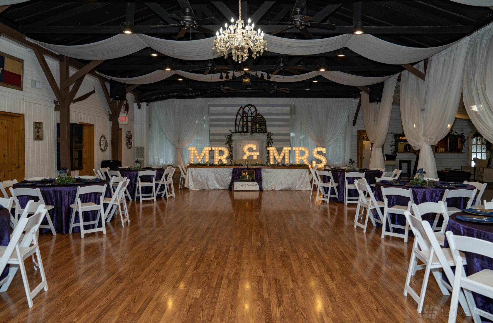 An event space in a house with wood floors, draped ceilings, a chandelier, and MR & MRS marquee lights at Lonesome Dove.