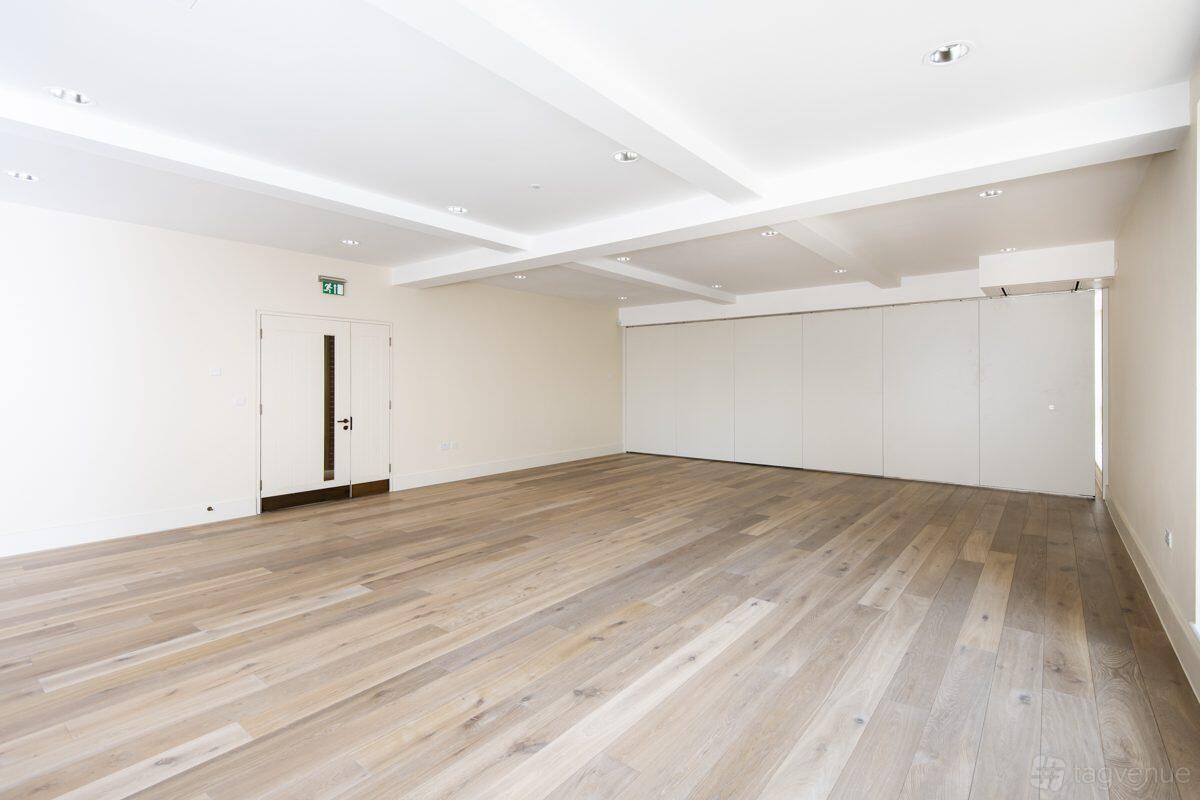 A meeting room with light wooden flooring, white walls, and a ceiling with recessed lighting at Toynbee Hall.