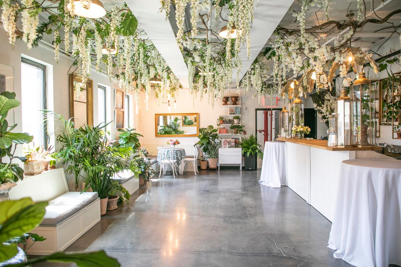 An event venue with hanging floral arrangements, potted plants, and polished floors at ILA Penthouse.