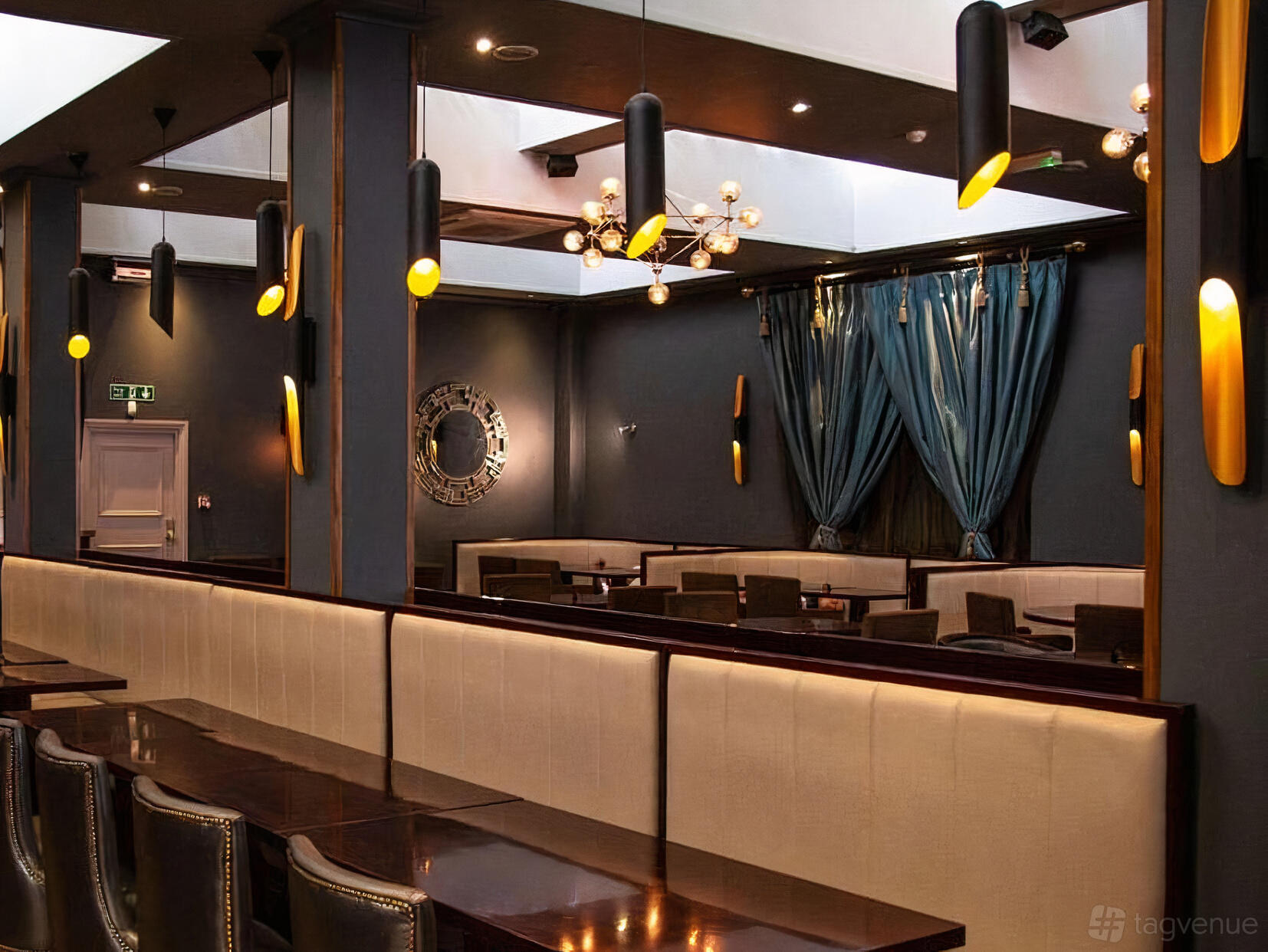 A restaurant with dark wood tables, upholstered bench seating, and gold-accented pendant lighting at Imperial Lounge & Restaurant.