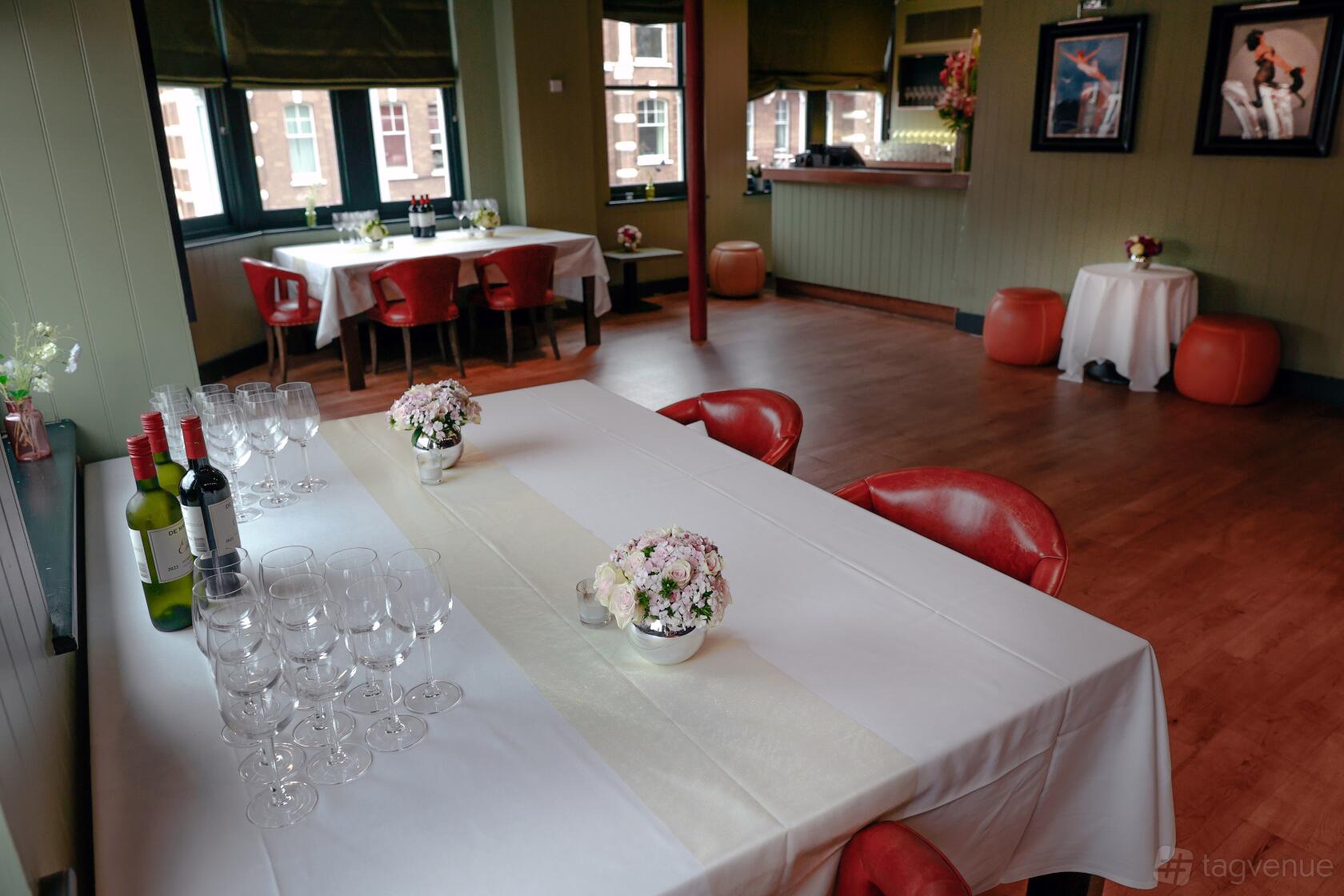 A dining room with red chairs, white tablecloths, floral centerpieces, and natural light at Albert's at Beaufort House.