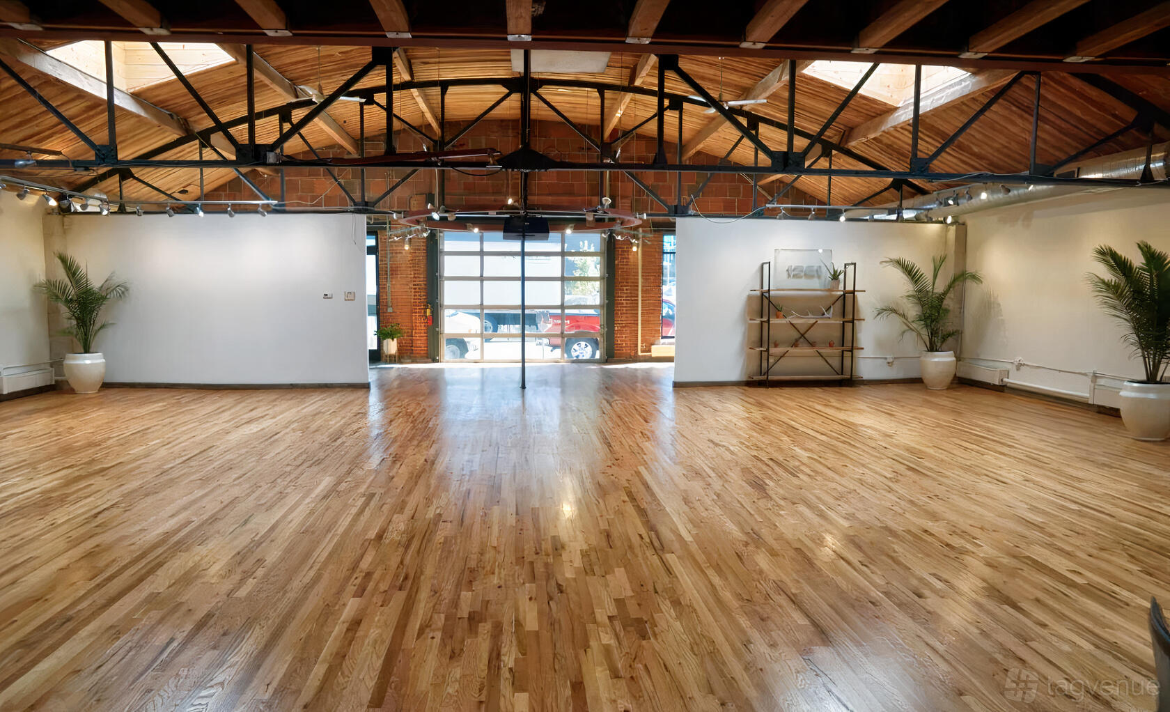 An event venue with hardwood floors, exposed wooden beams, and large windows at Sterling Event Space.