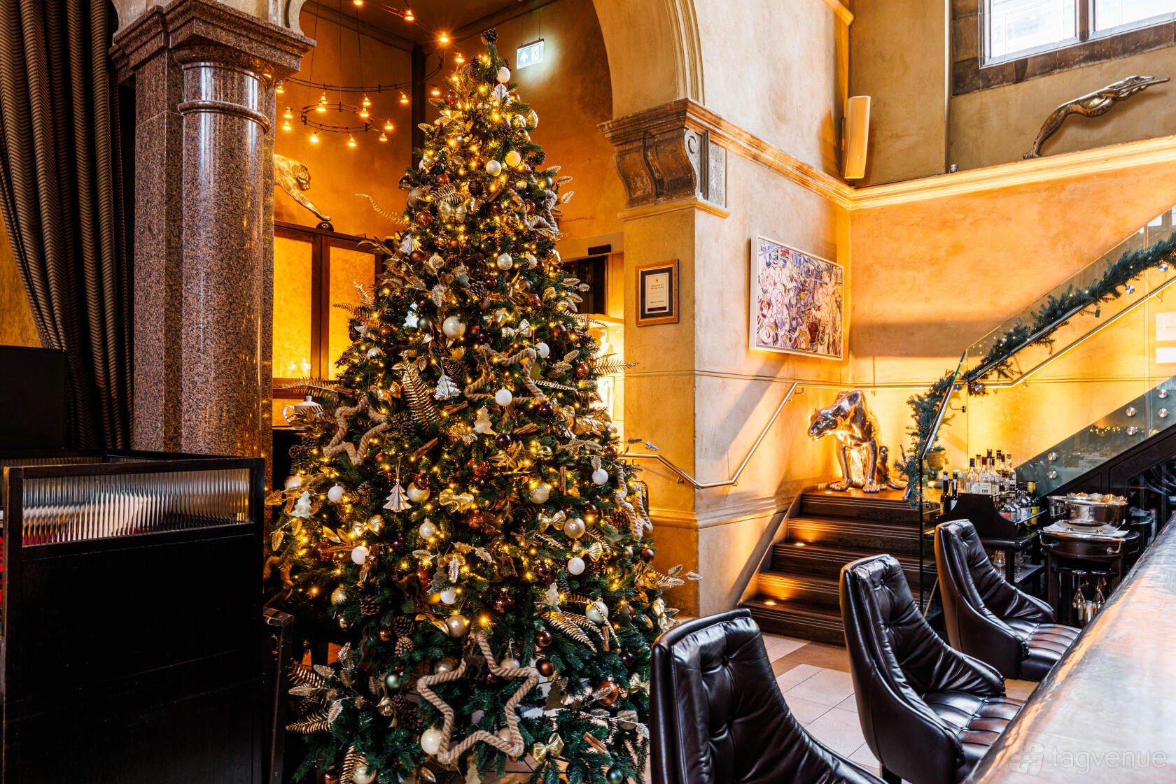 A restaurant with a decorated Christmas tree, marble columns, and a grand staircase at Galvin La Chapelle.