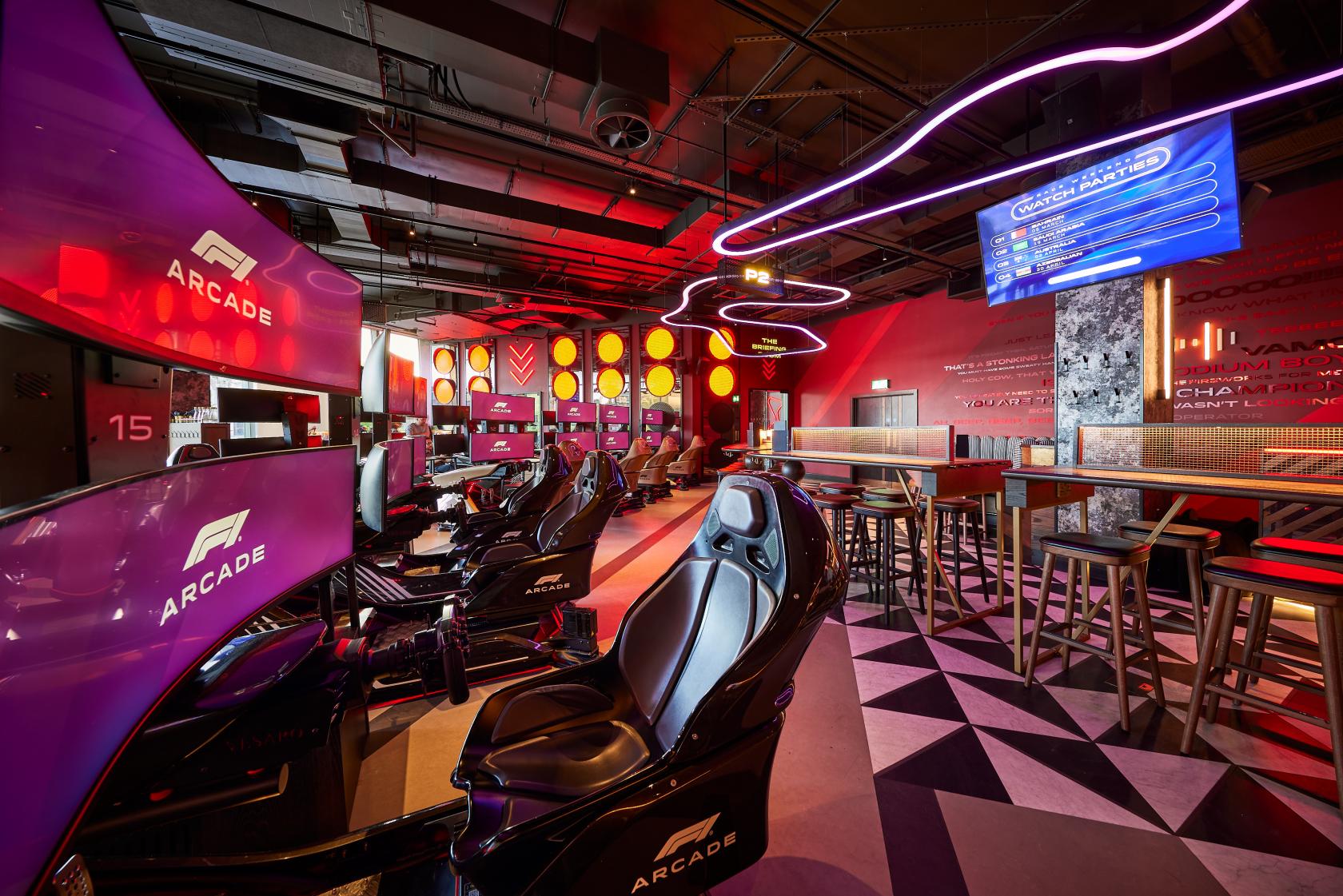 A cocktail bar with racing simulators, neon lighting, and high tables at F1 Arcade, St Pauls, London.