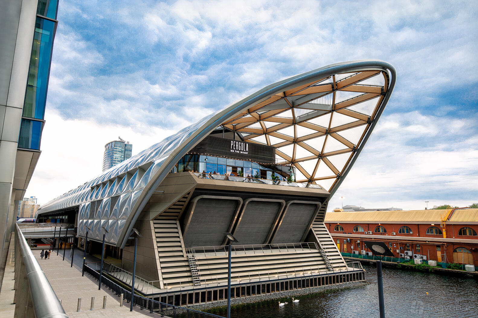A waterside restaurant with a glass and wood canopy roof and riverside terrace at Pergola on The Wharf.