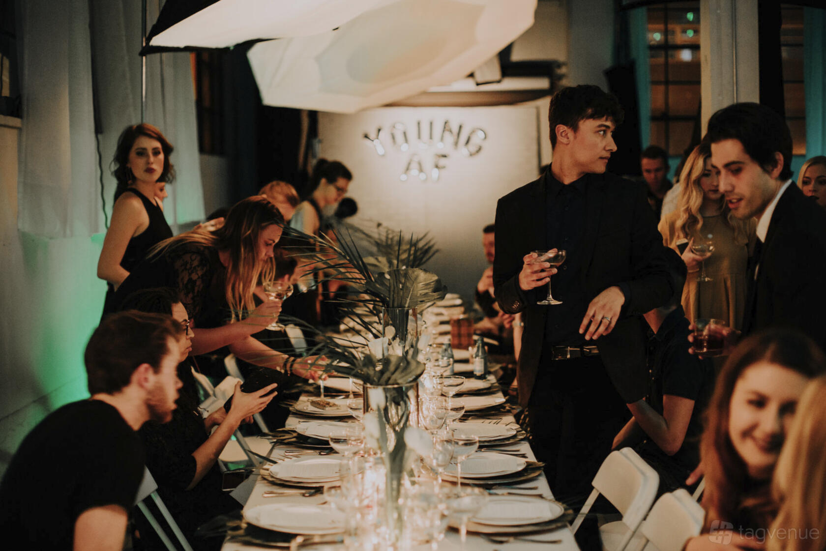 A photo studio with long banquet table, white plates, palm centerpieces, and overhead softbox lighting at Studio G Seattle.