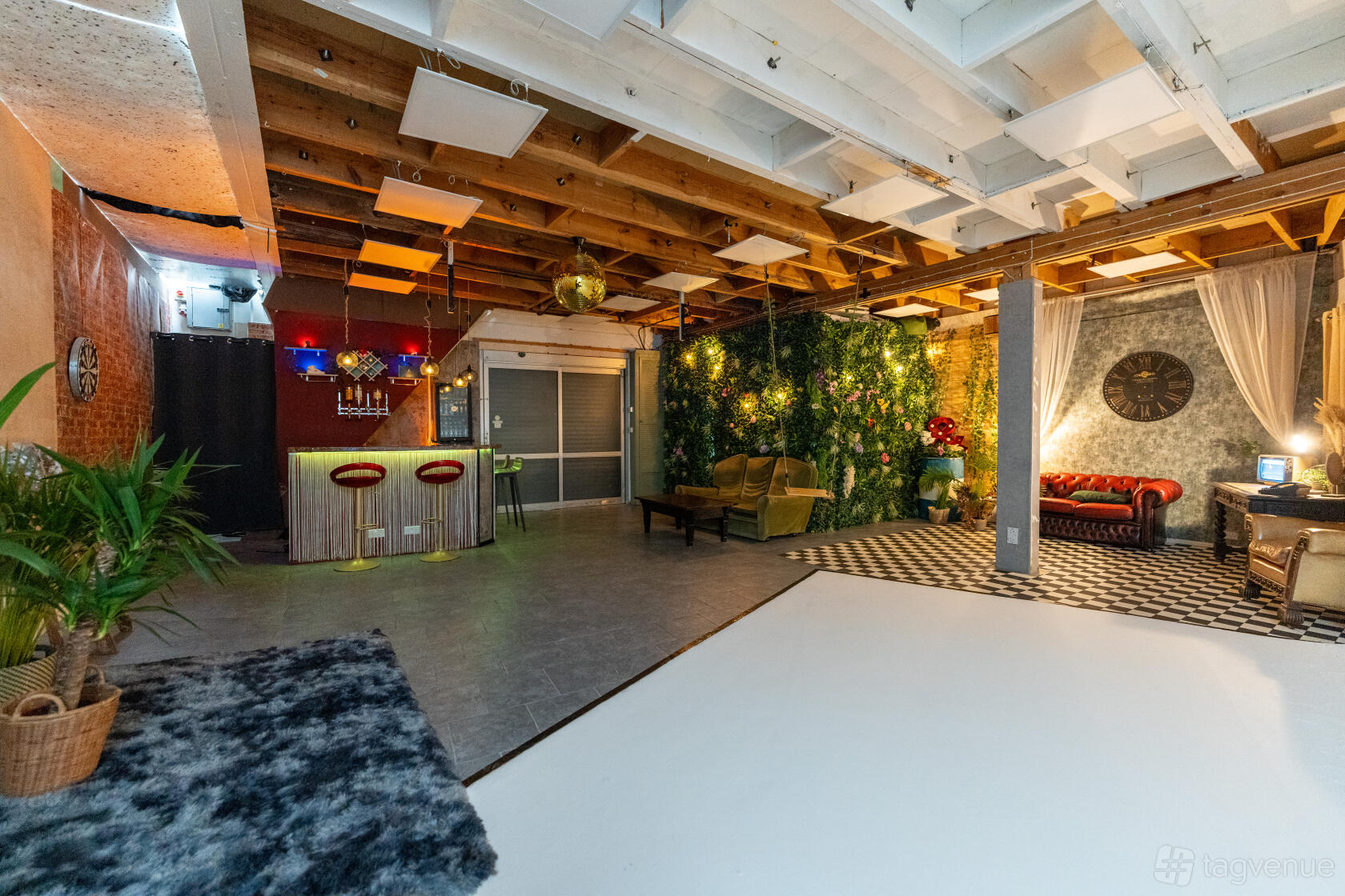 A photo and film studio with exposed wooden ceilings, faux greenery wall, lounge seating, and a bar at 6 Degrees studio.