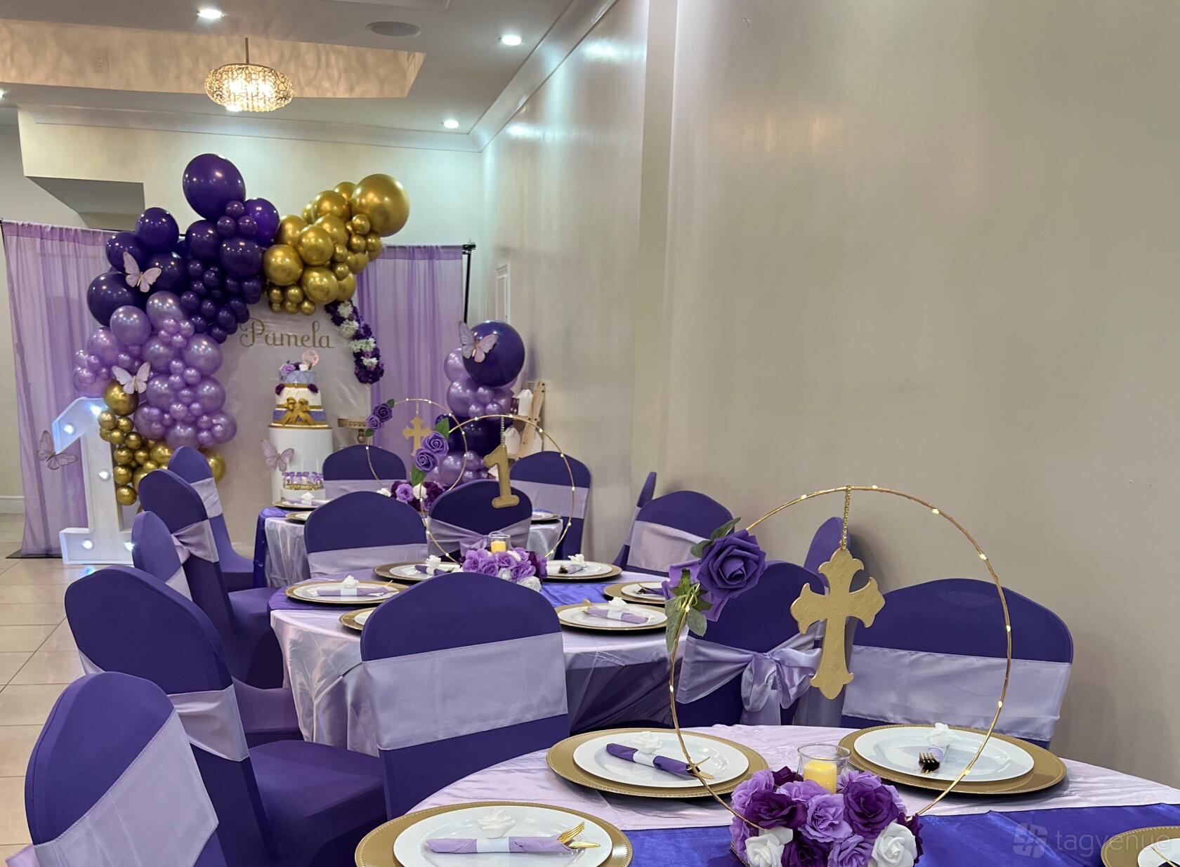 An event venue with round tables featuring purple and gold decorations and draped chairs at Jashn Events Space.