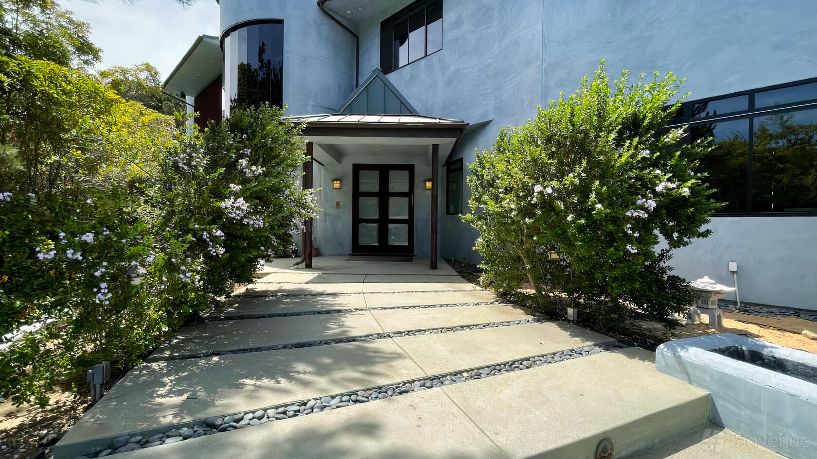 A film and photo studio with a concrete walkway lined by flowering shrubs at Hillside Luxurious Mansion.