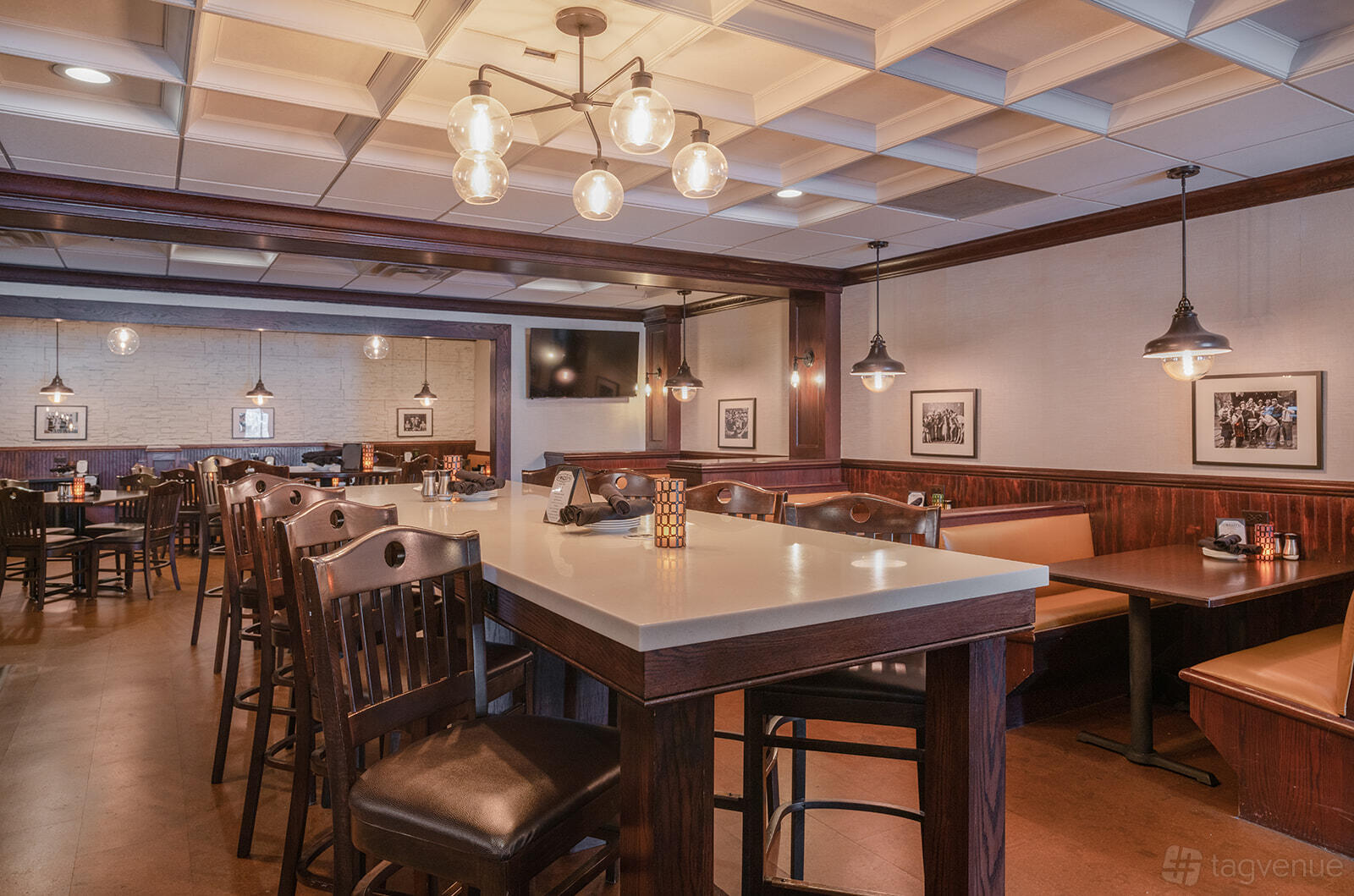 A pub interior with dark wood furniture, pendant lighting, framed photos, and a high communal table at O'Malley's Pub.