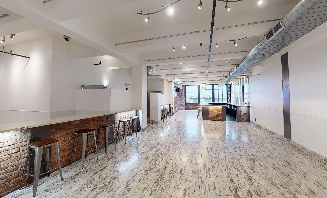 A hall with open floor space, exposed ductwork, brick accents, and large industrial windows at Loft Life Venue 53 Edison.