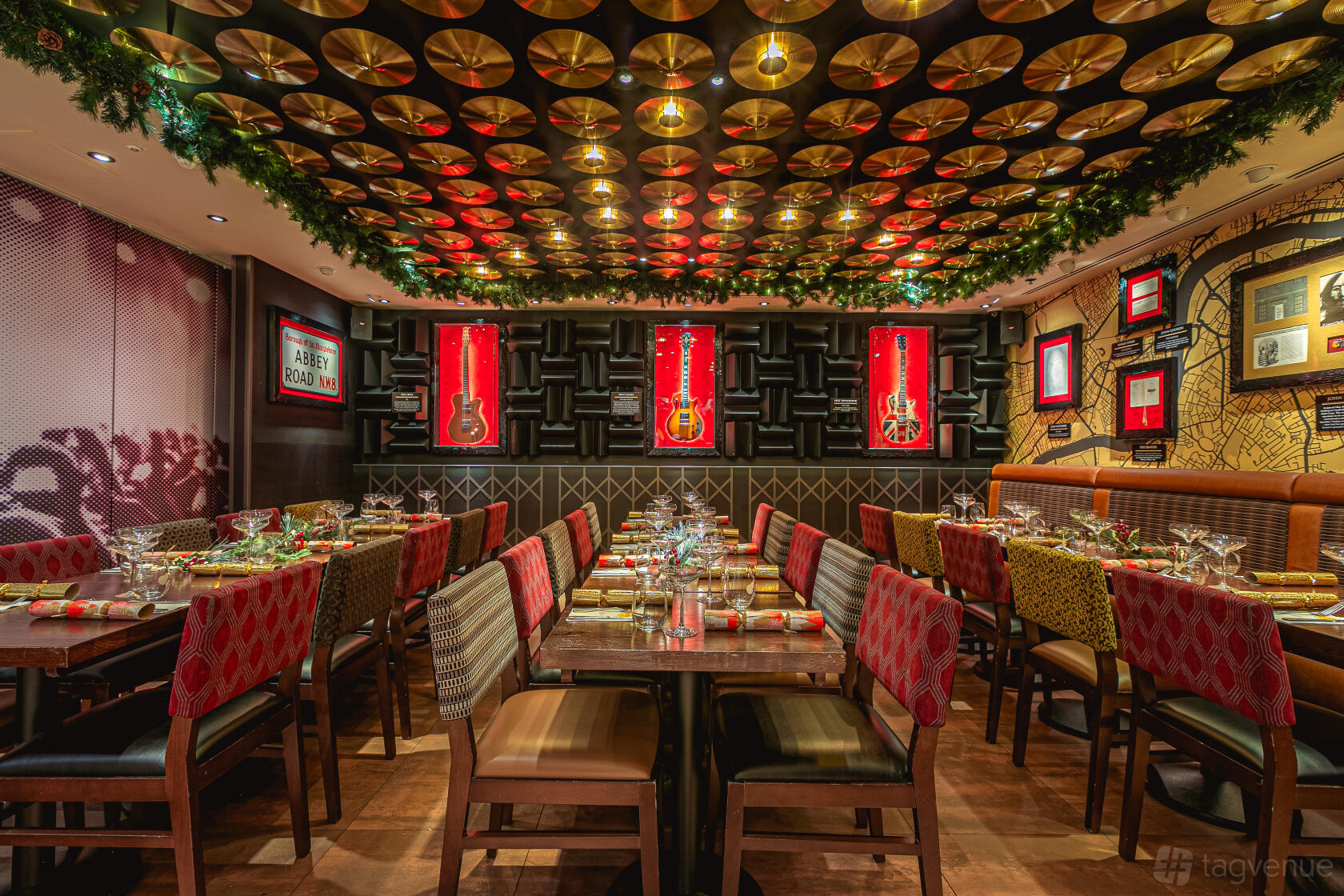 A dining room with gold records on the ceiling, guitar wall displays, and long banquet tables at Hard Rock Cafe Piccadilly Circus.