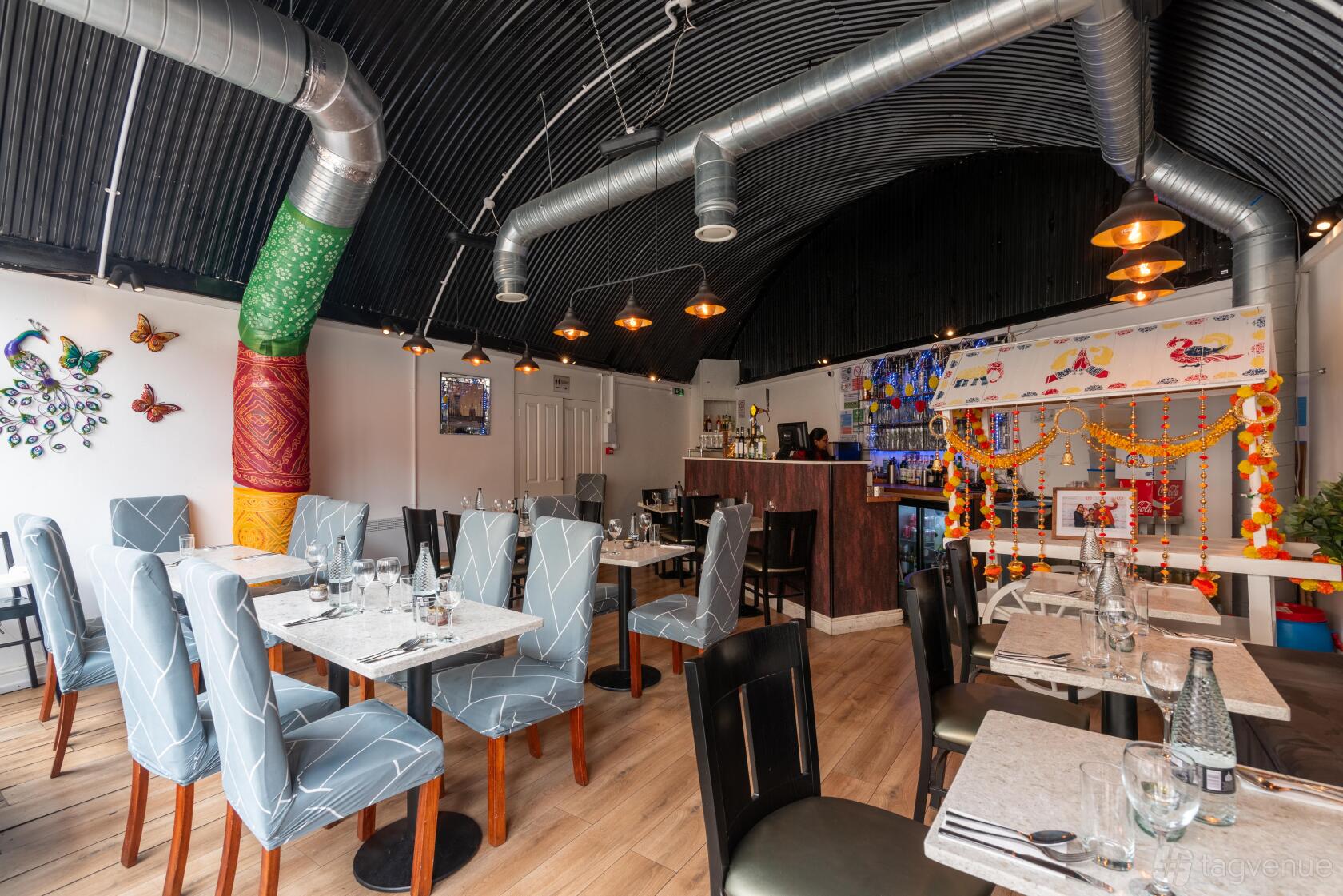 A restaurant with curved black ceiling, pendant lights, decorated bar area, and tables set with glassware at Delhi wala Food.