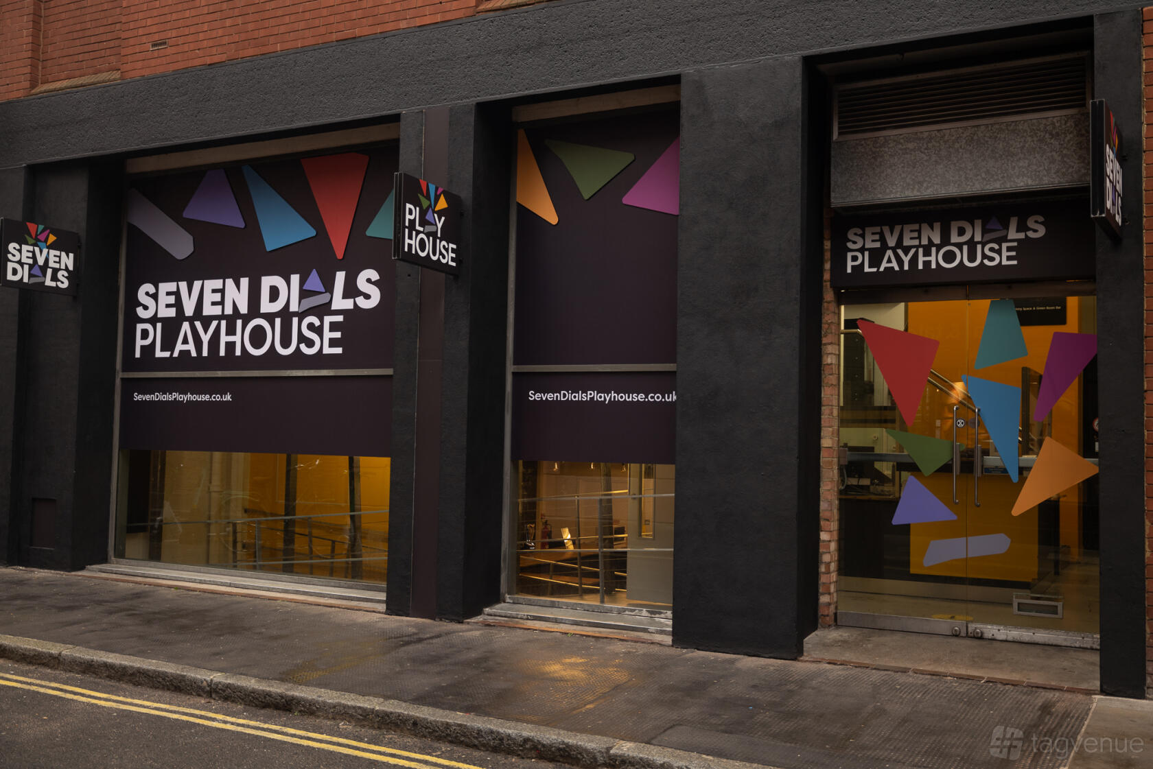 A theatre entrance with large glass windows, geometric signage, and colorful shapes at Seven Dials Playhouse.