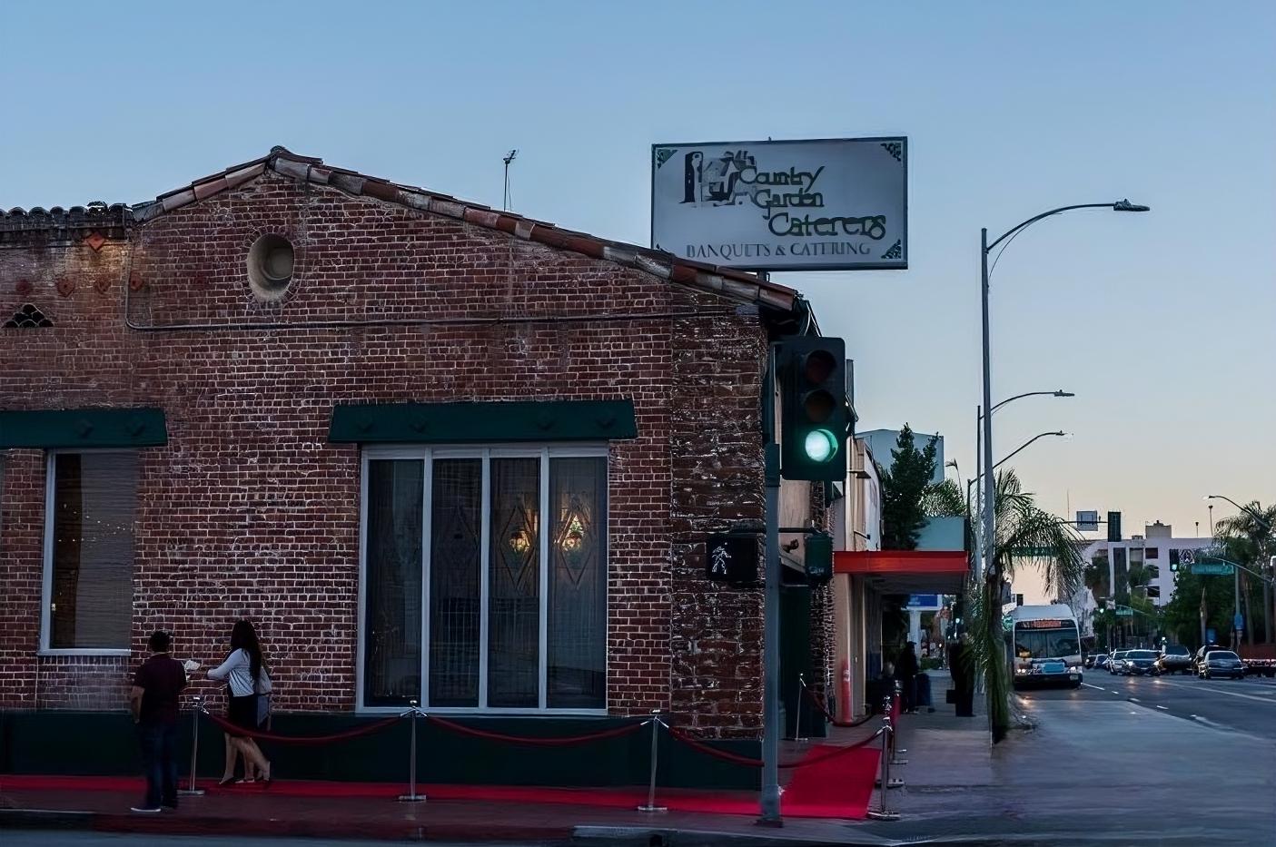 A versatile event space with exposed brick exterior, green awnings, and a marquee sign at Country Garden Caterers.