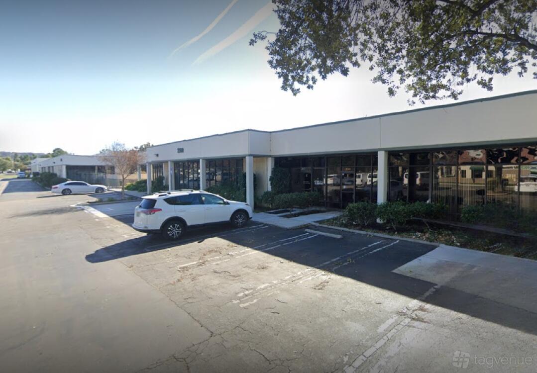 A versatile event space with a single-story white exterior, large windows, and landscaped bushes at Club Energy.