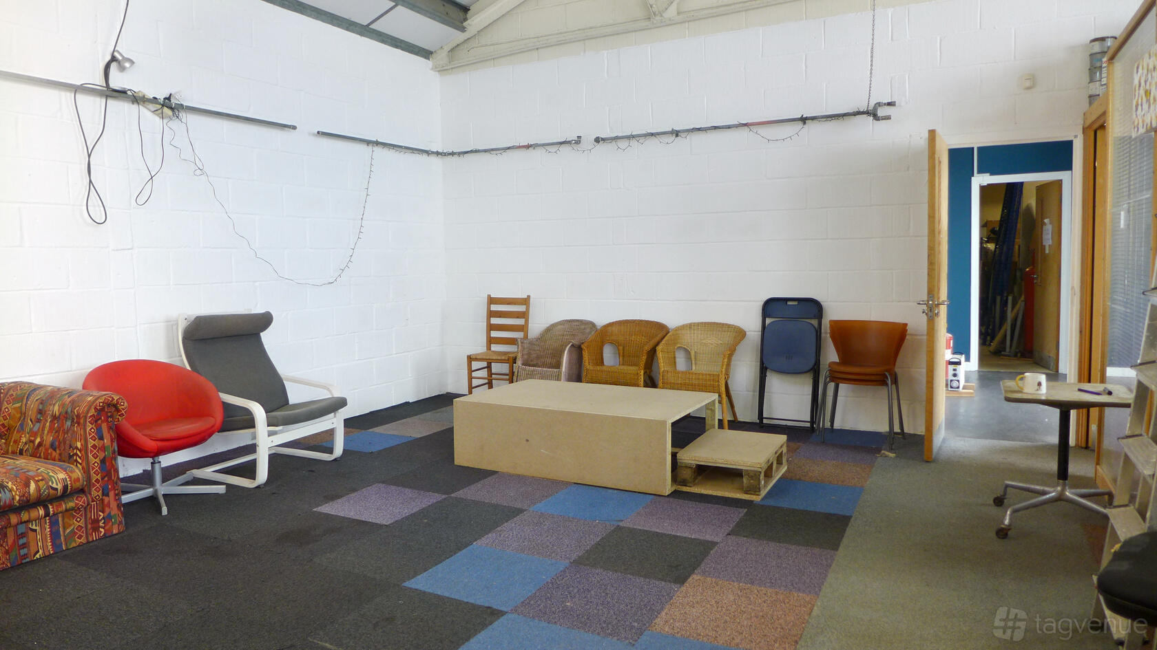 A creative warehouse space with mismatched chairs, modular tables, and colorful floor tiles at Aurelia Art Studios.