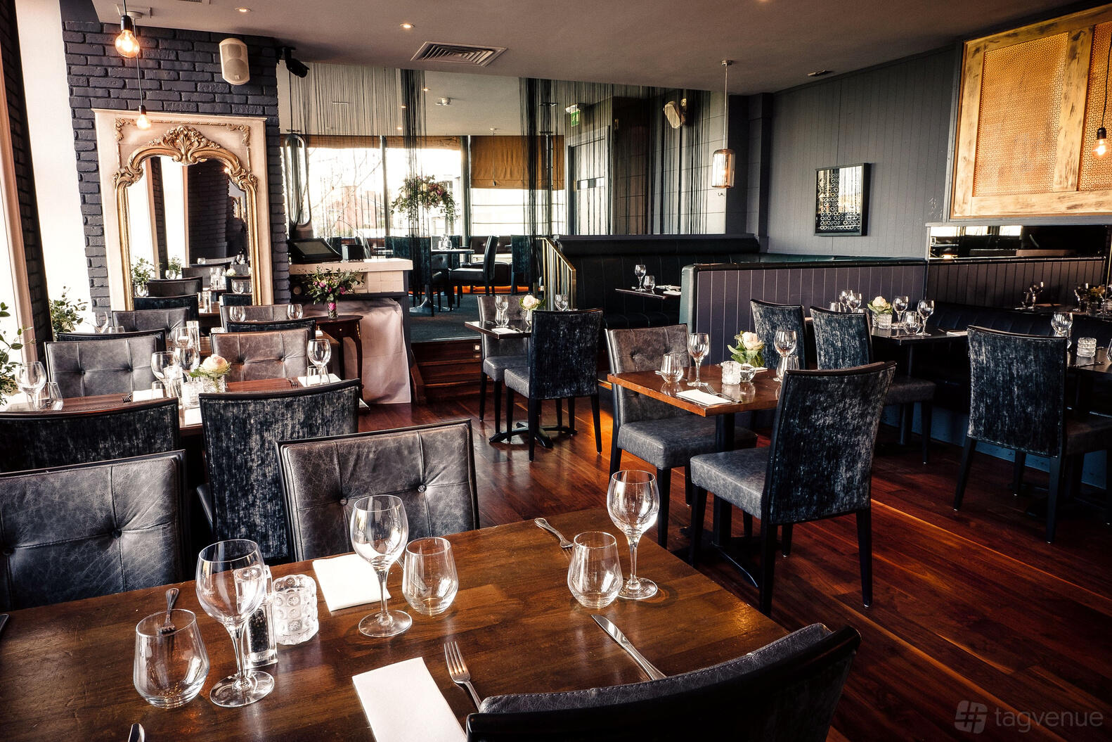 A restaurant with dark leather chairs, wooden tables set with glassware, and large decorative mirrors at Wrights Findlater Howth.