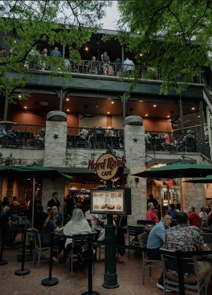 A restaurant and bar with a stone facade, second-floor balcony seating, and outdoor umbrellas at Howl at the Moon, San Antonio.
