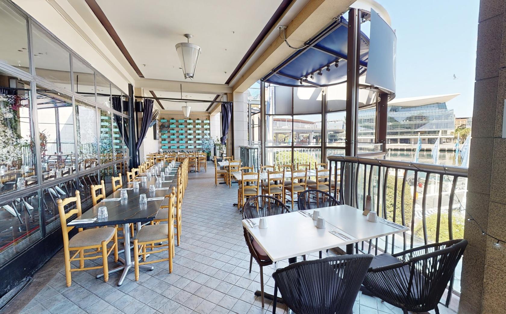 An outdoor patio with tiled flooring, wooden chairs, and black tables overlooking a city view at Blackbird Cafe.