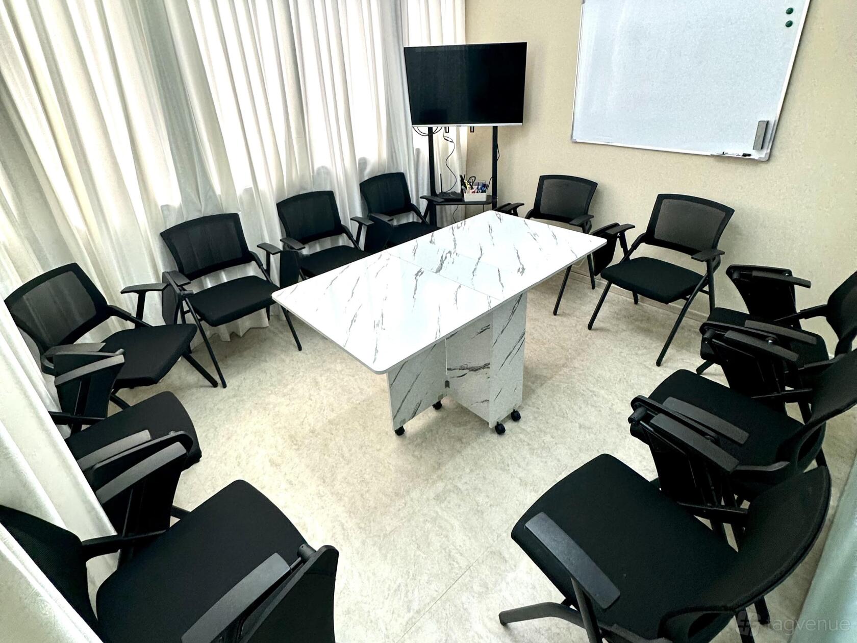 A meeting centre with a marble-top rectangular table, black chairs in a circle, TV screen, and whiteboard at Faith Rental Space.