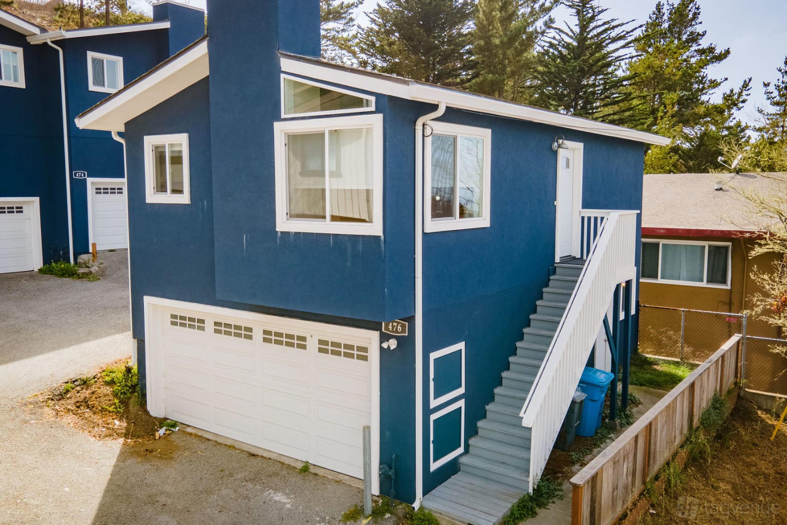 A blue apartment with a white garage door and exterior staircase at Private Townhome