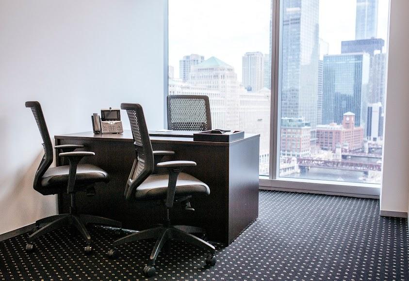 A meeting centre workspace with a dark wood desk, two office chairs, and floor-to-ceiling windows at Servcorp - River Point.