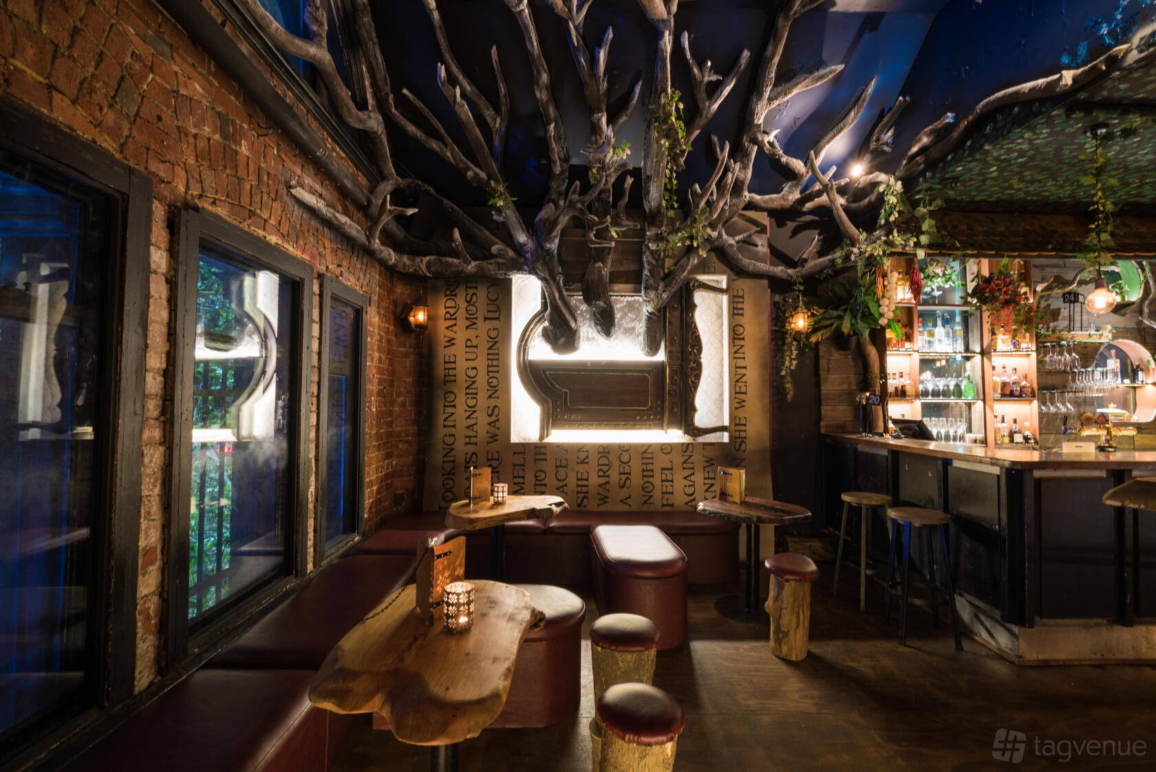 An event space in a bar with exposed brick walls, tree branch ceiling decor, and booth seating at Storyville.