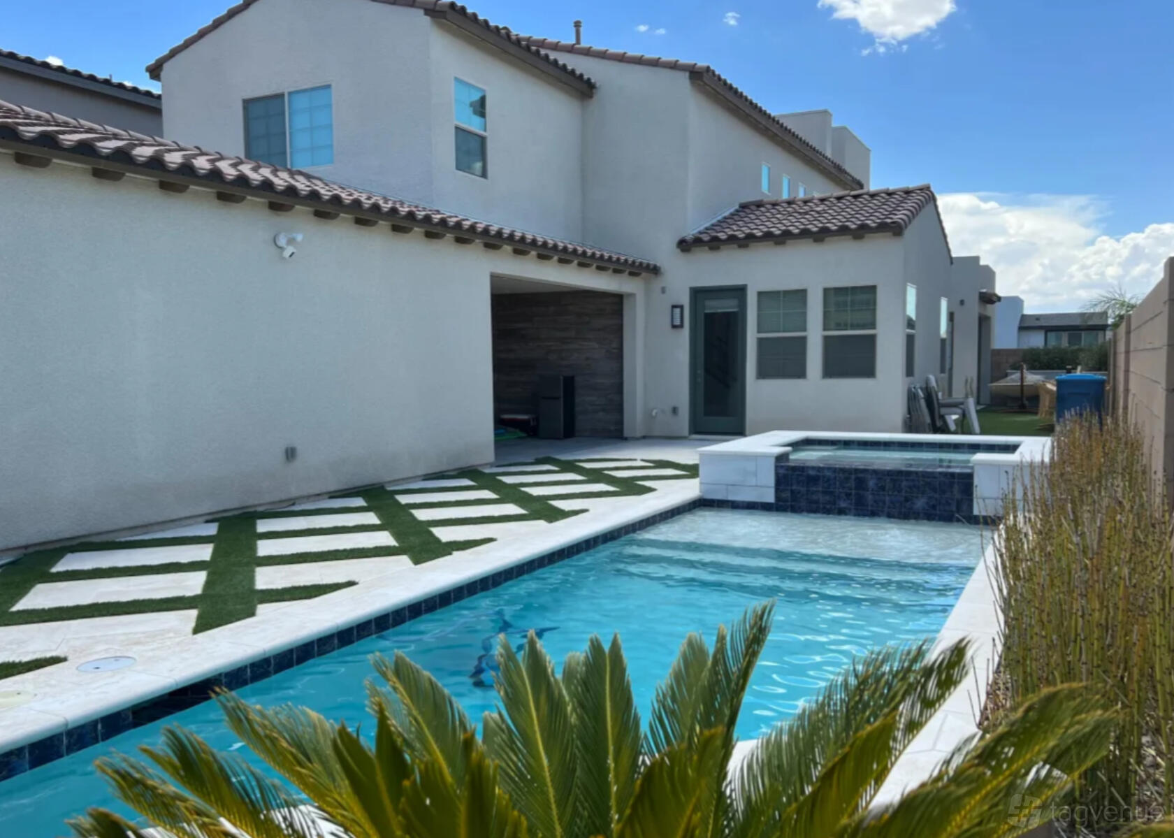 A house with a swimming pool, spa, and geometric tile patio at Luxury Henderson Home with Pool and Spa.
