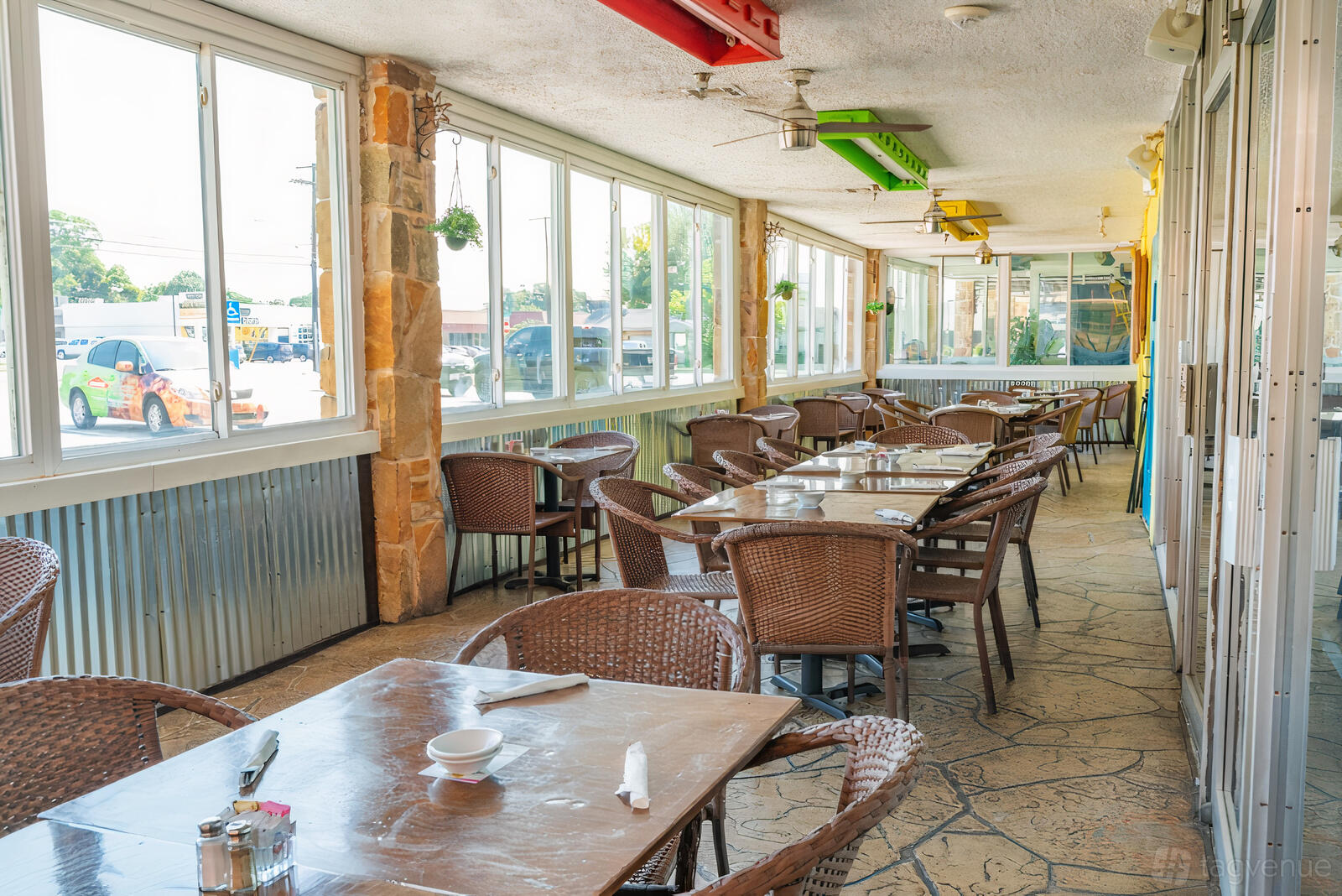 A terrace at a restaurant with wicker chairs, stone flooring, and large windows at Miguelito's Mexican Restaurant.