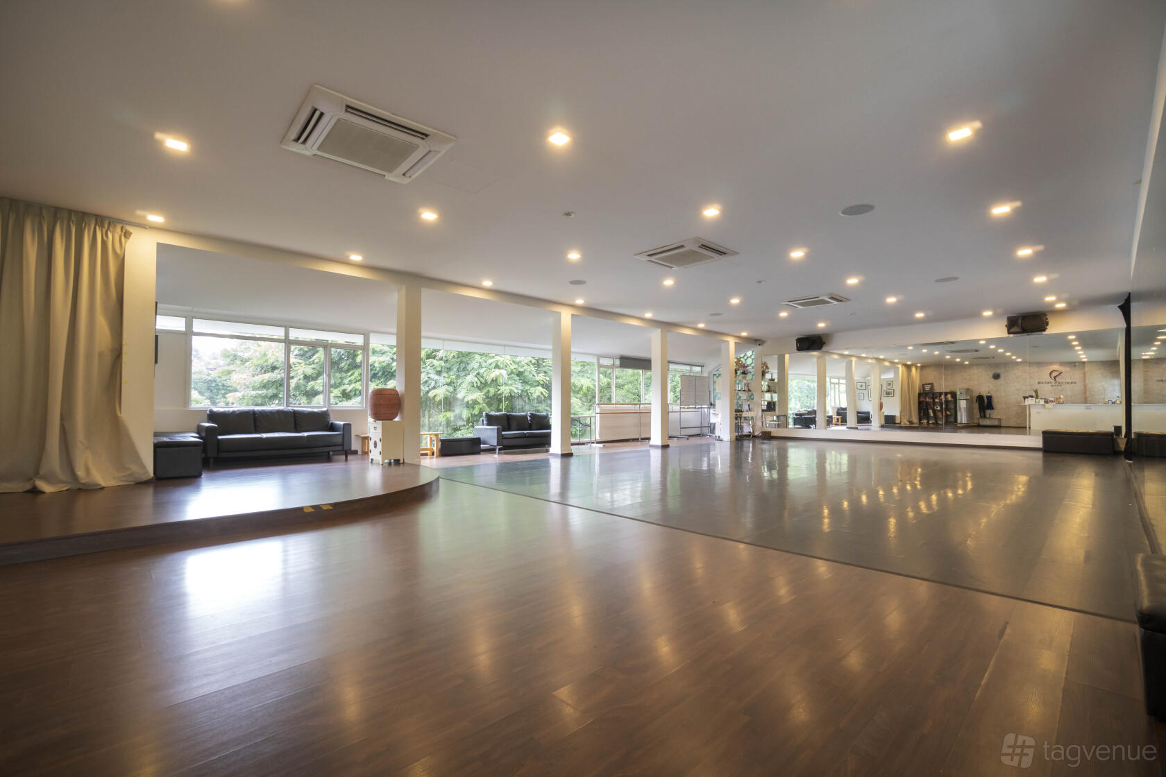 A spacious dance studio with floor-to-ceiling mirrors, wood floors, and large windows at Dancer's Dream Studio.