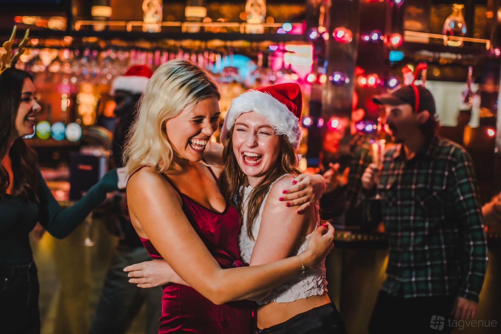 An event venue with festive holiday decor, warm lighting, and people in Santa hats at Puttshack Watford.