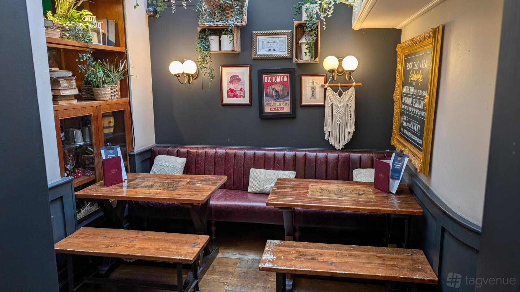 A pub dining room with wooden tables, leather banquette seating, wall art, and hanging plants at White Horse.