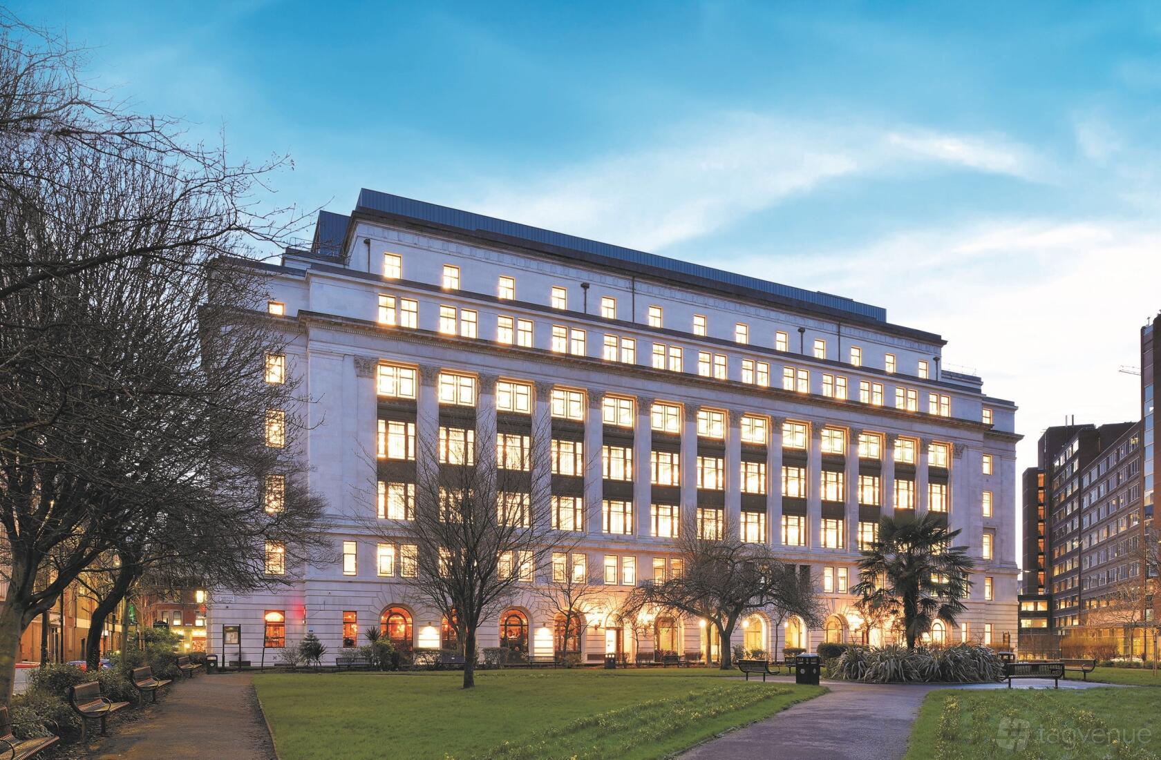 A meeting centre with a large neoclassical facade, illuminated windows, and landscaped gardens at Orega Manchester Arkwright House.