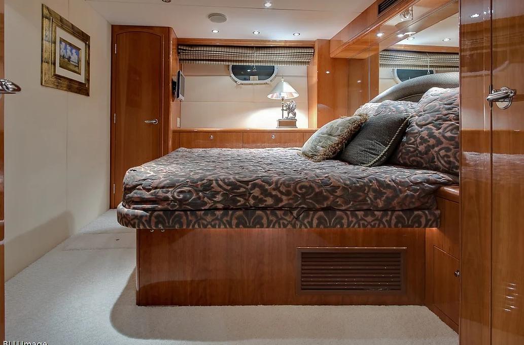 A yacht stateroom with a patterned bedspread, mirrored walls, and wood-paneled cabinetry at Lots Of Yachts/Lots Of Spots - New York.
